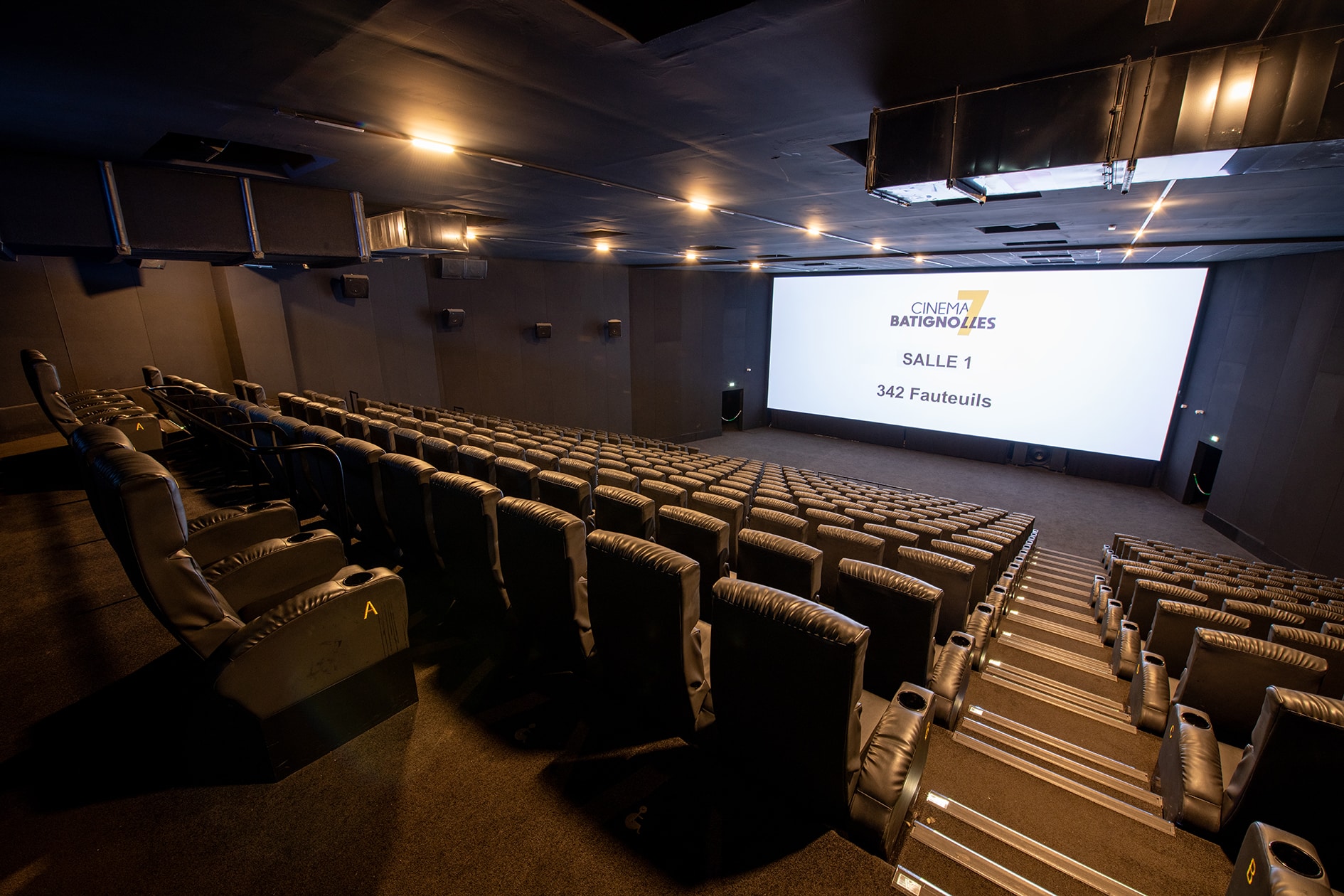 Grande salle de cinéma équipée de fauteuils en cuir noir et de la technologie Dolby.