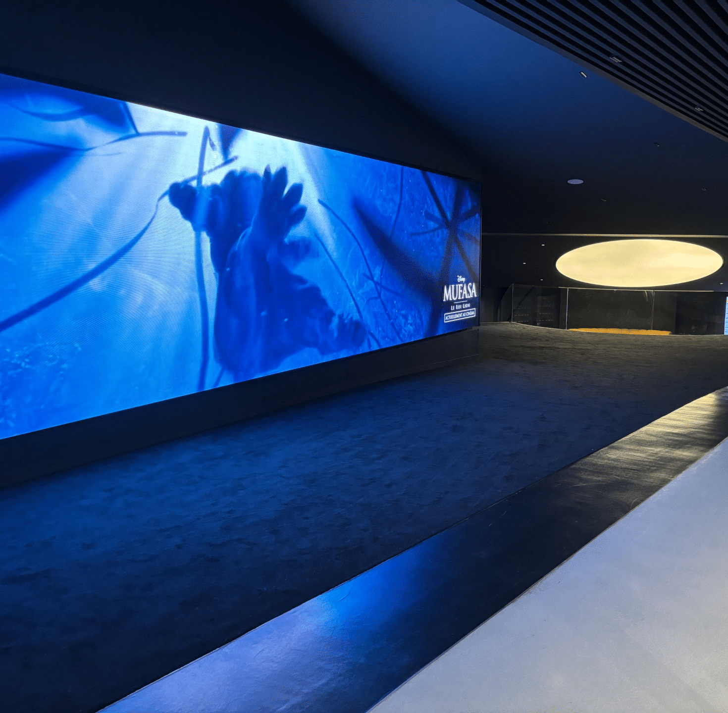 Couloir sombre avec écran géant affichant une image promotionnelle du film 