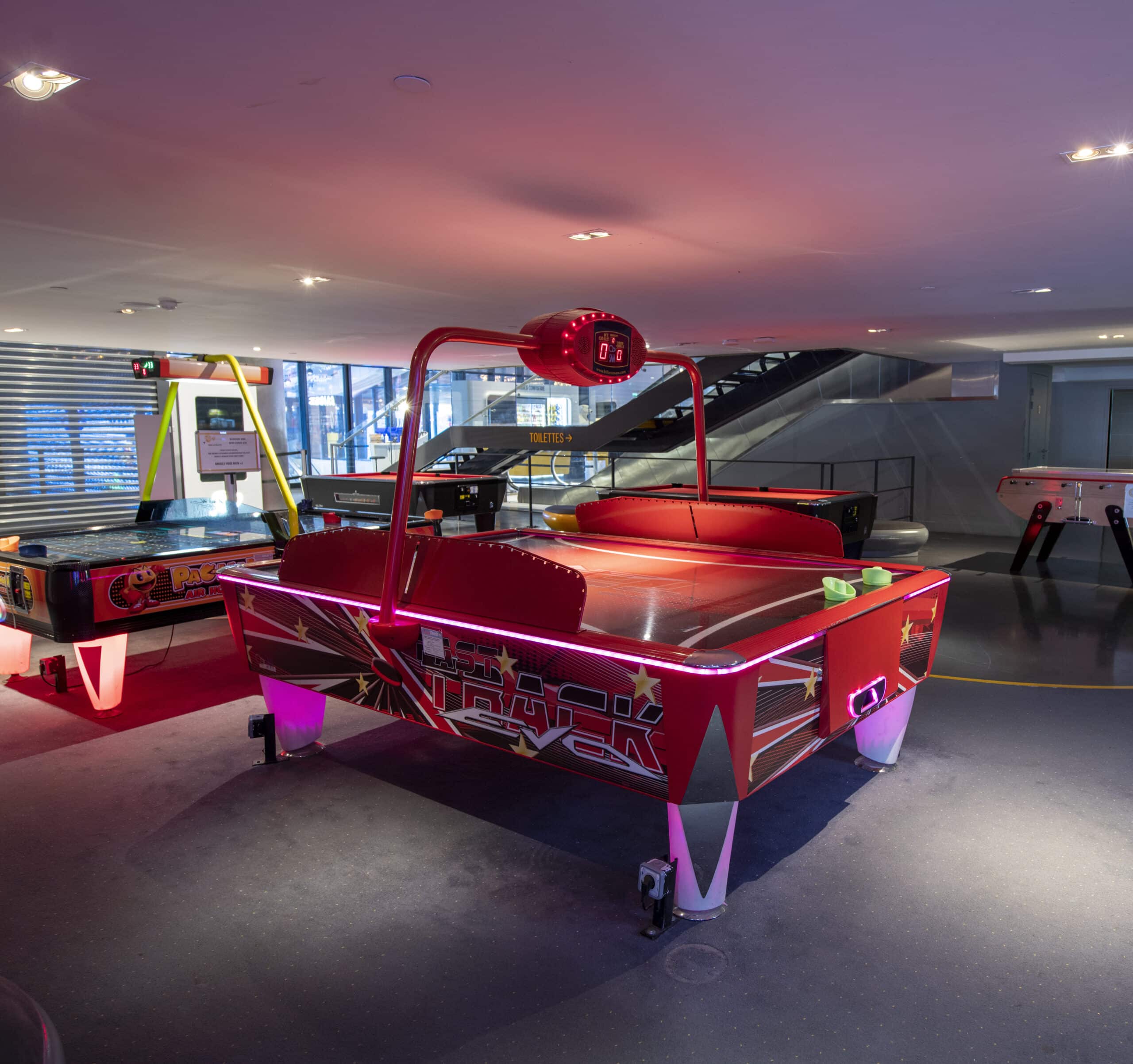 Espace Pathé Games avec différentes machines d’arcade et de jeux vidéo, éclairage néon coloré, ambiance moderne et ludique, proposant des jeux pour tous les âges dans un cadre convivial.