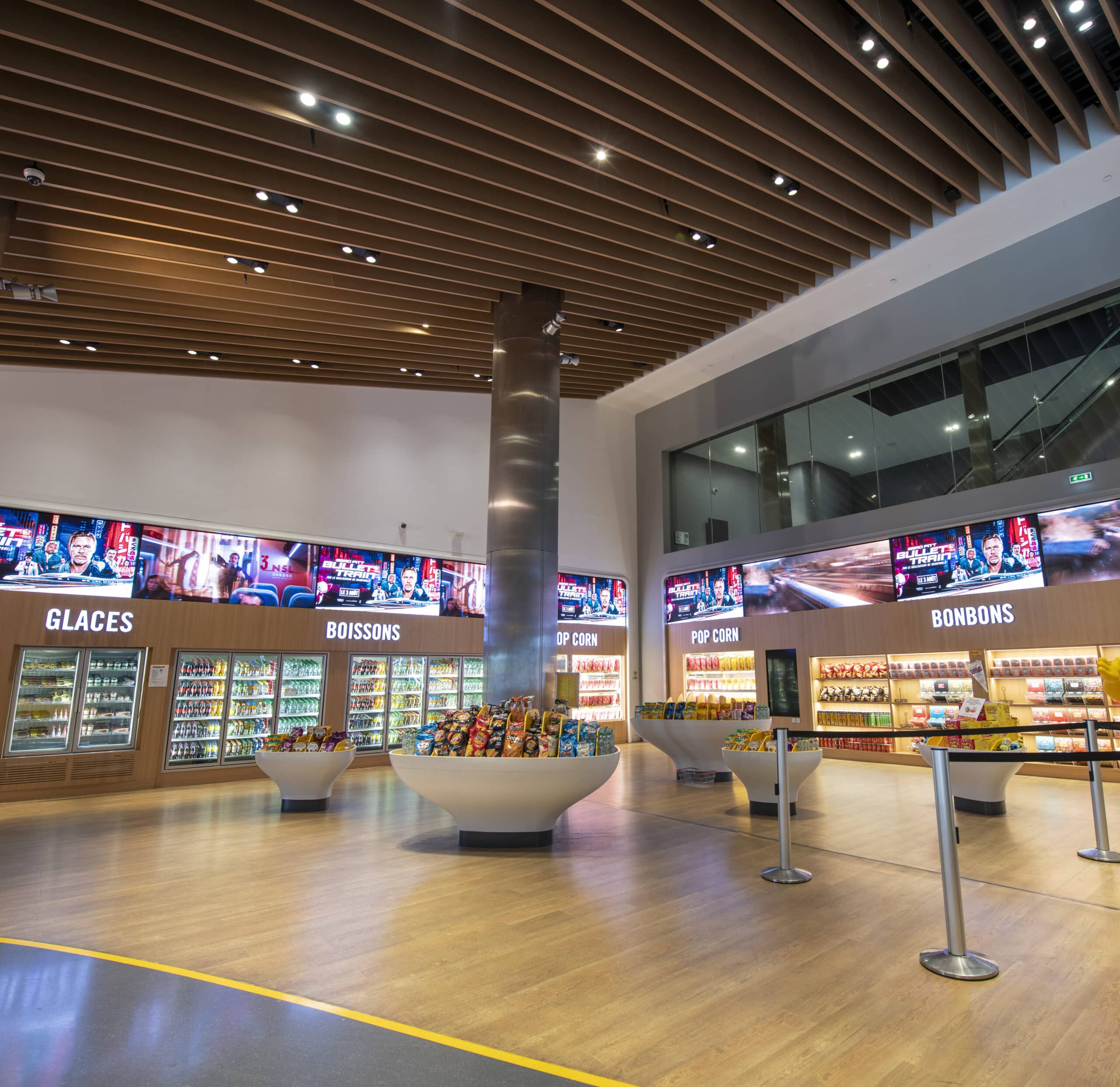Espace confiserie du cinéma Pathé avec comptoir de pop-corn, distributeurs de boissons en libre-service et îlots de snacks et confiseries.