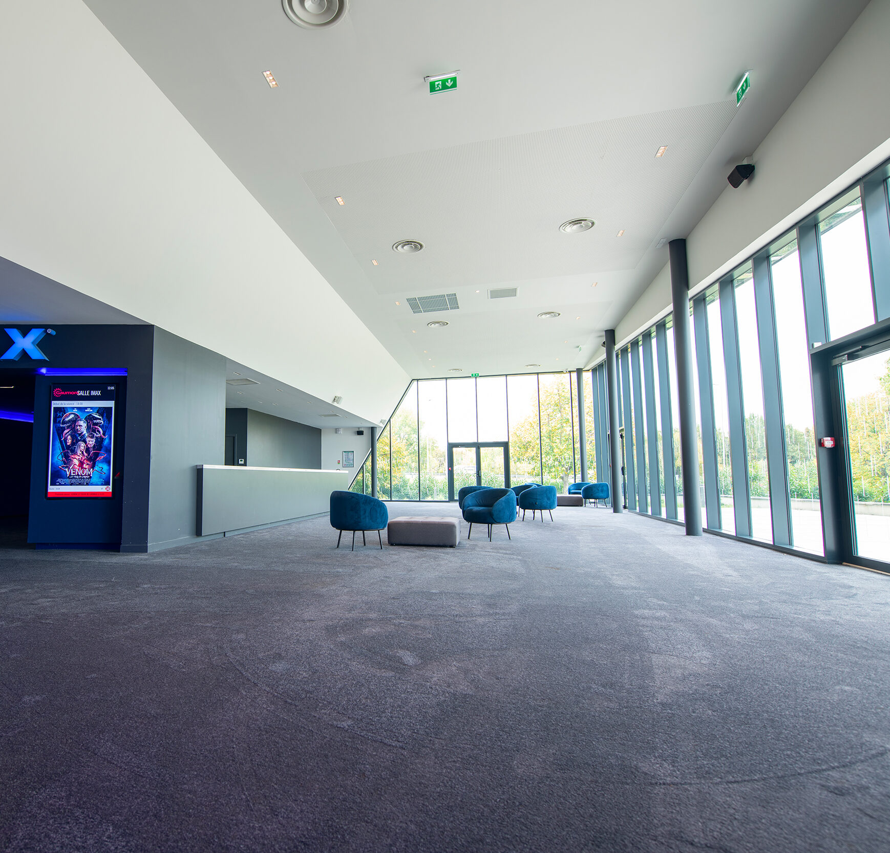 Espace de réception entouré de baies vitrées avec mobilier de réception.