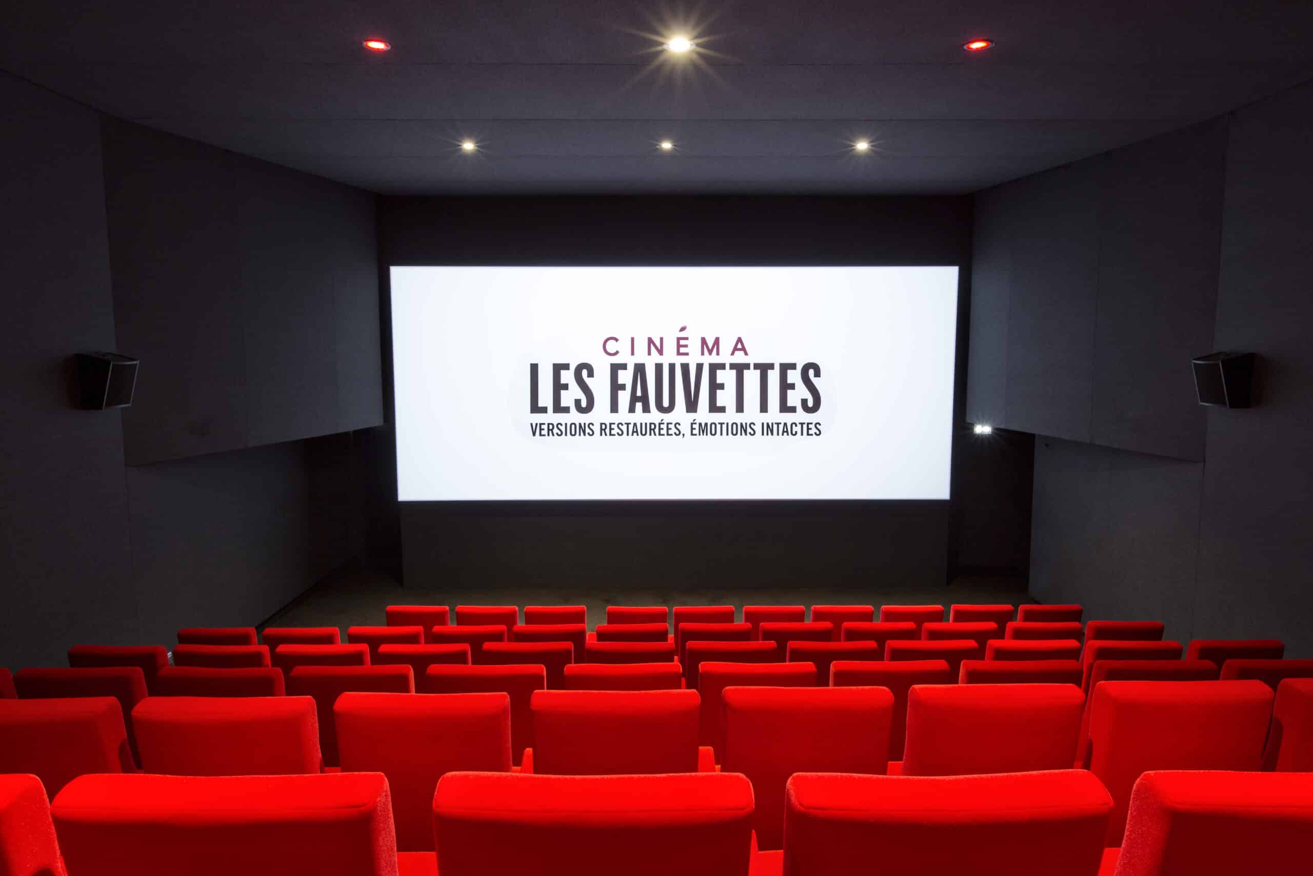Vue depuis l’arrière d'une salle de cinéma du Pathé Les Fauvettes avec ses rangées de fauteuils en velours rouges orientés vers l’écran.