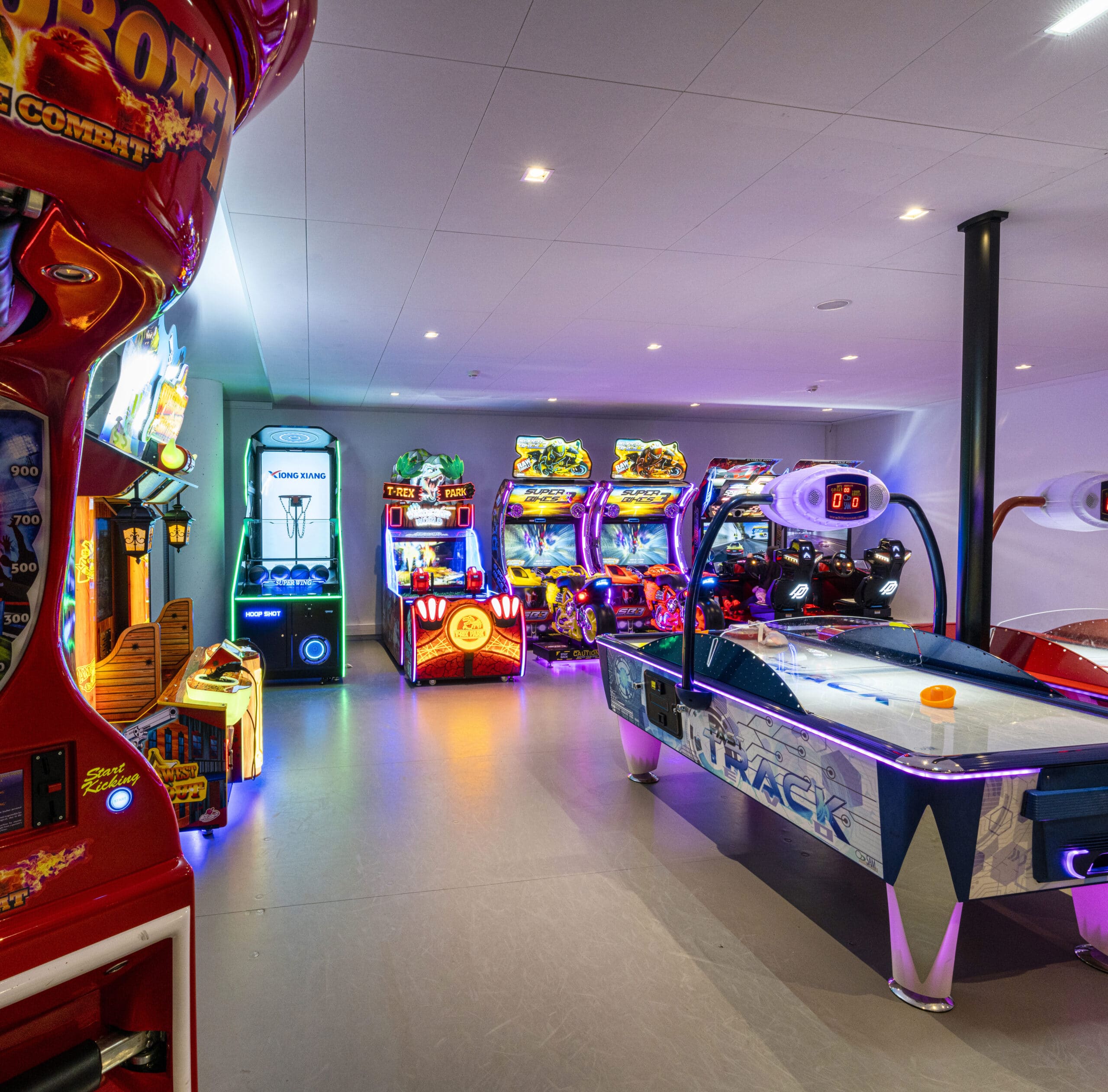 Espace Pathé Games avec différentes machines d’arcade et de jeux vidéo, éclairage néon coloré, ambiance moderne et ludique, proposant des jeux pour tous les âges dans un cadre convivial.