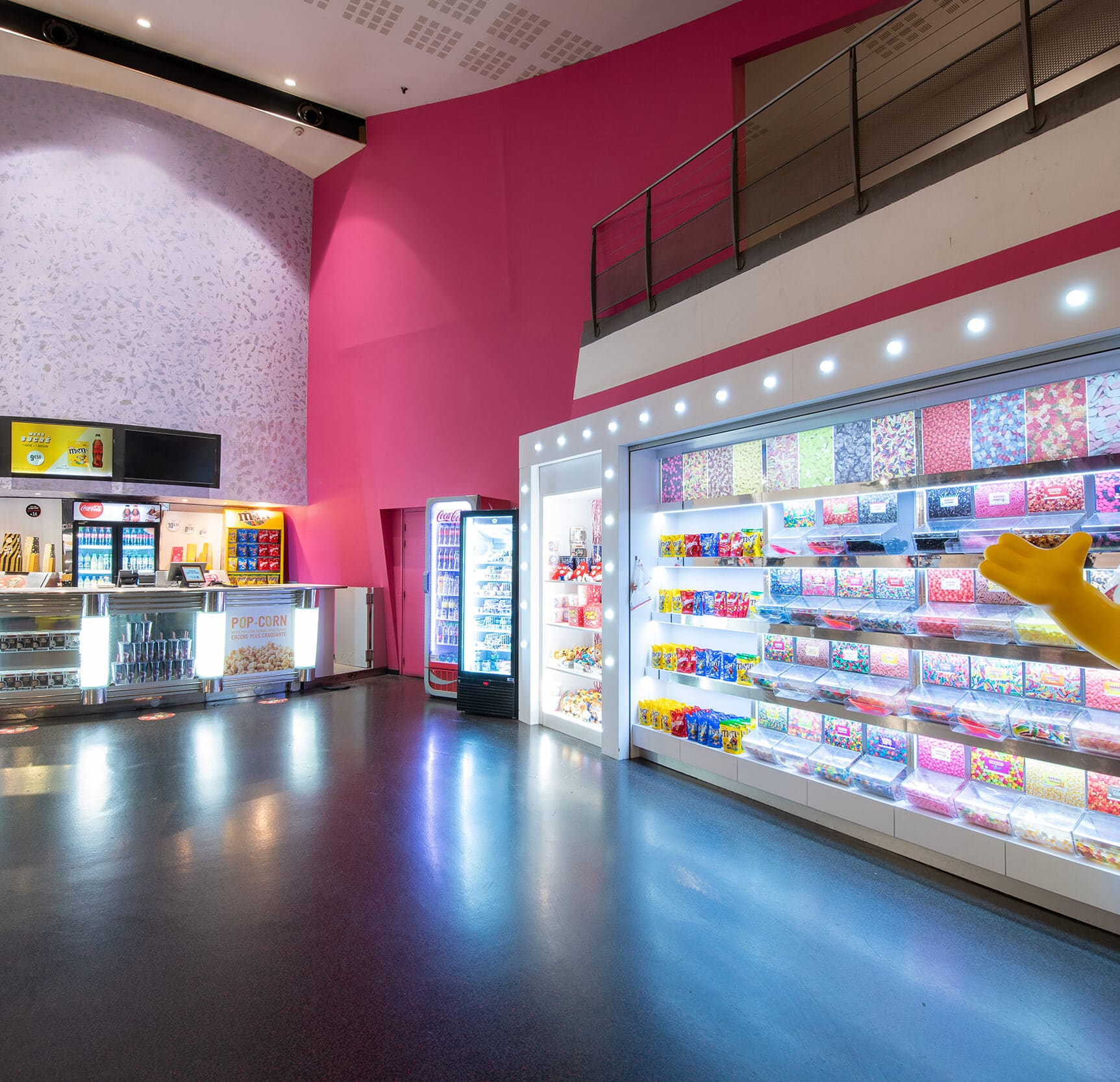 Espace confiserie du cinéma Pathé avec comptoir de pop-corn, distributeurs de boissons en libre-service et îlots de snacks et confiseries.