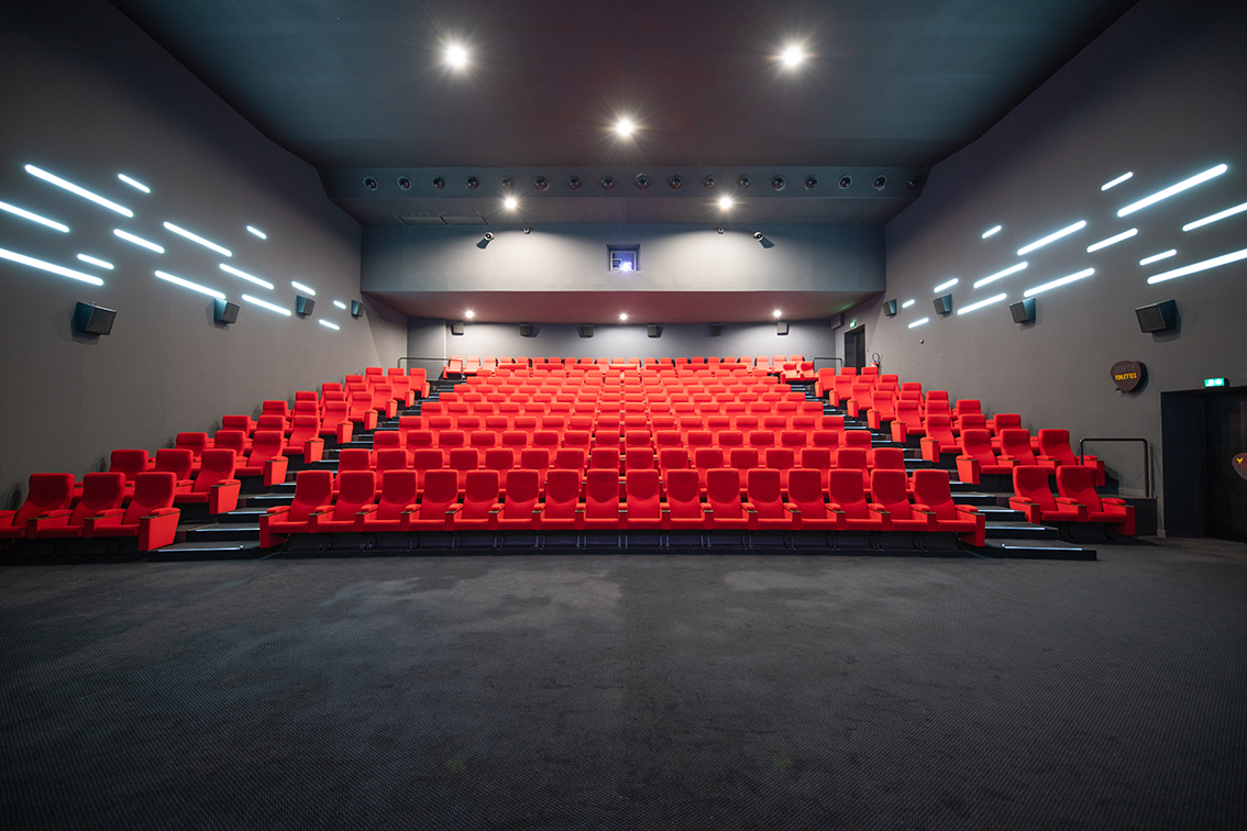 Vu d'ensemble de face d'une grande salle avec ses fauteuils en velours rouge.