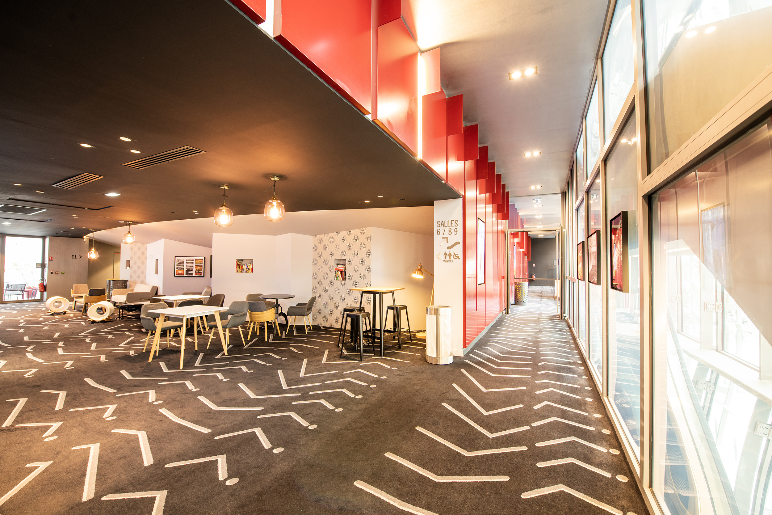 Espace cocktail du cinéma, équipé de tables, chaises et canapés, idéal pour des moments conviviaux et des réceptions, à proximité de notre espace Café Caché.