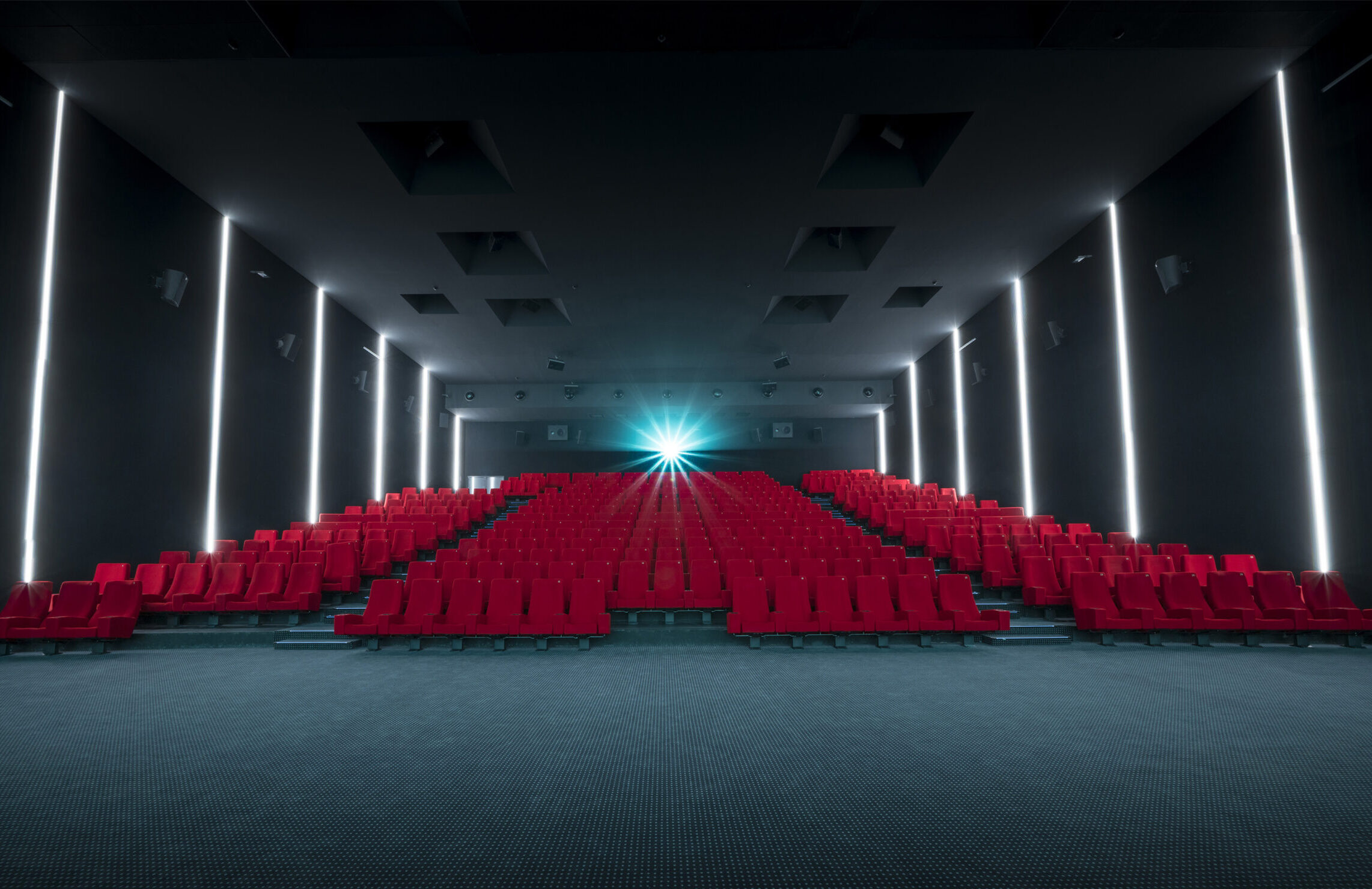 Vu d'ensemble de face d'une grande salle avec ses fauteuils en velours rouge.