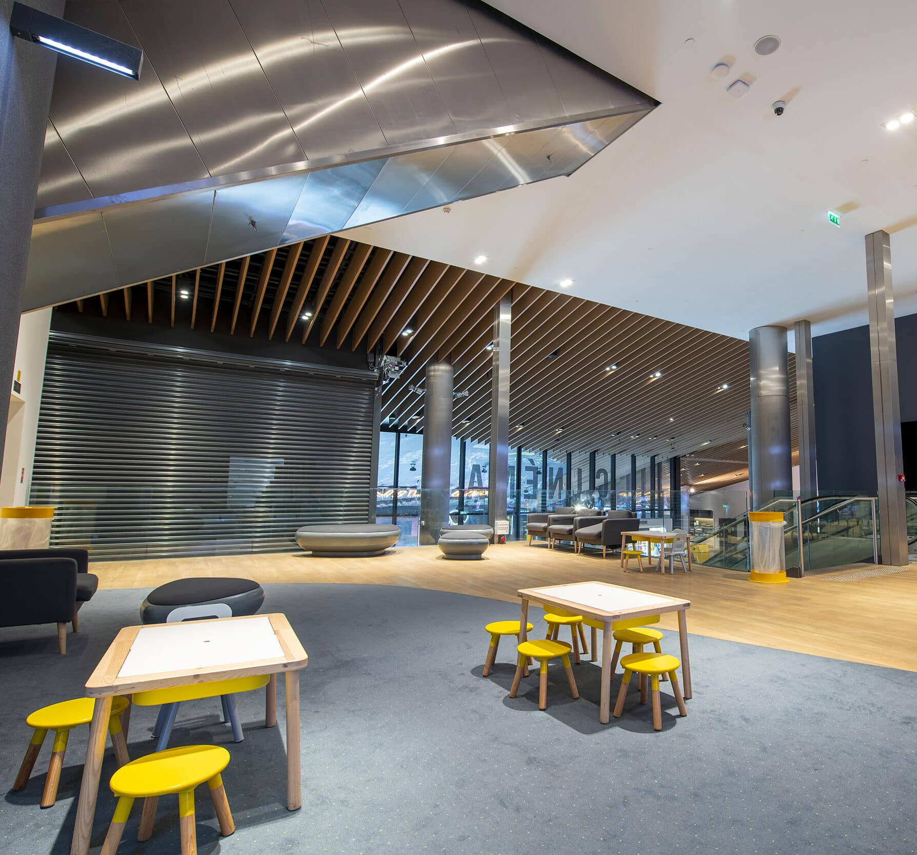 Espace cocktail situé sur la mezzanine du cinéma, éclairé par une lumière blanche et aménagé avec du mobilier de réception.
