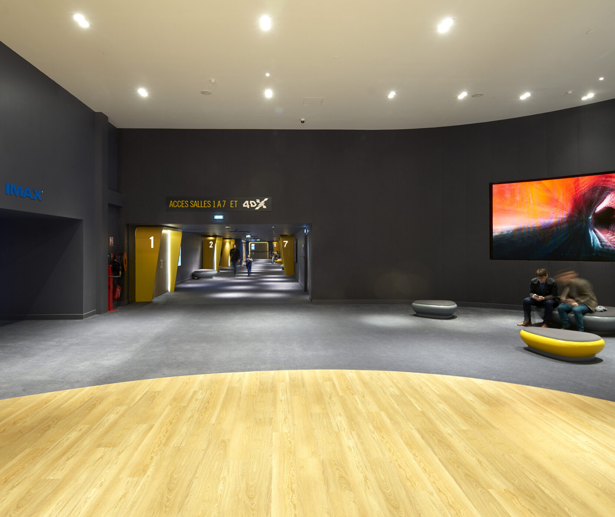Espace de réception dans le hall du cinéma, éclairé par une lumière blanche et aménagé avec du mobilier.