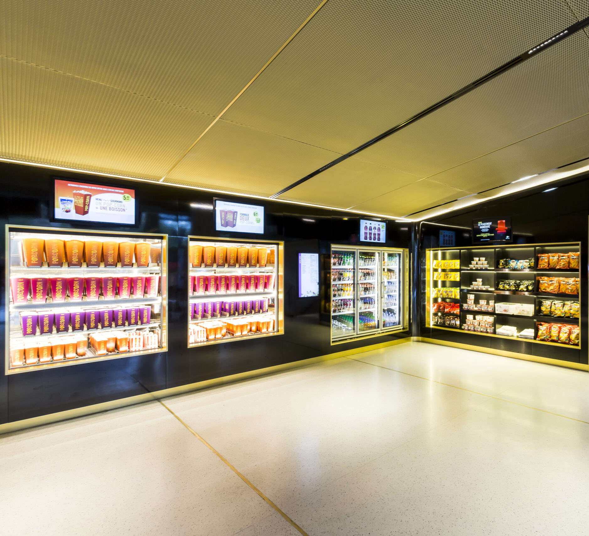 Espace confiserie du cinéma Pathé avec comptoir de pop-corn, distributeurs de boissons en libre-service et îlots de snacks et confiseries.