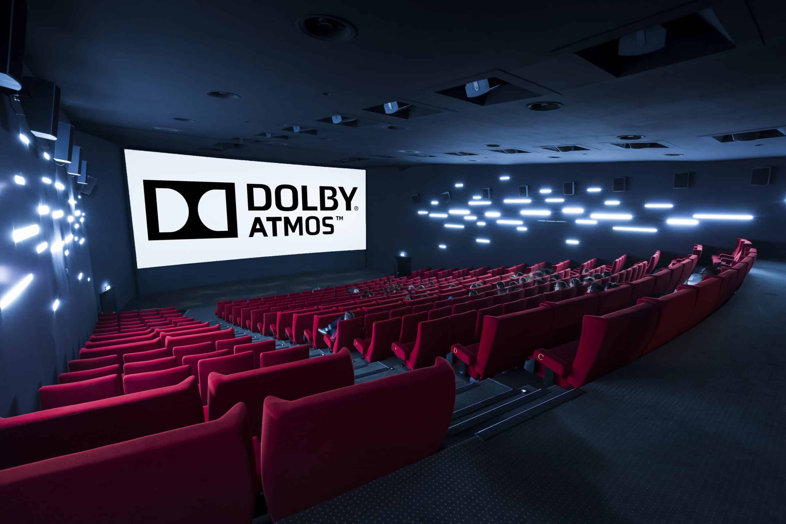 Vue depuis l’arrière d'une salle de cinéma avec la technologie Dolby Atmos et ses rangées de fauteuils en velours rouges orientés vers l’écran.