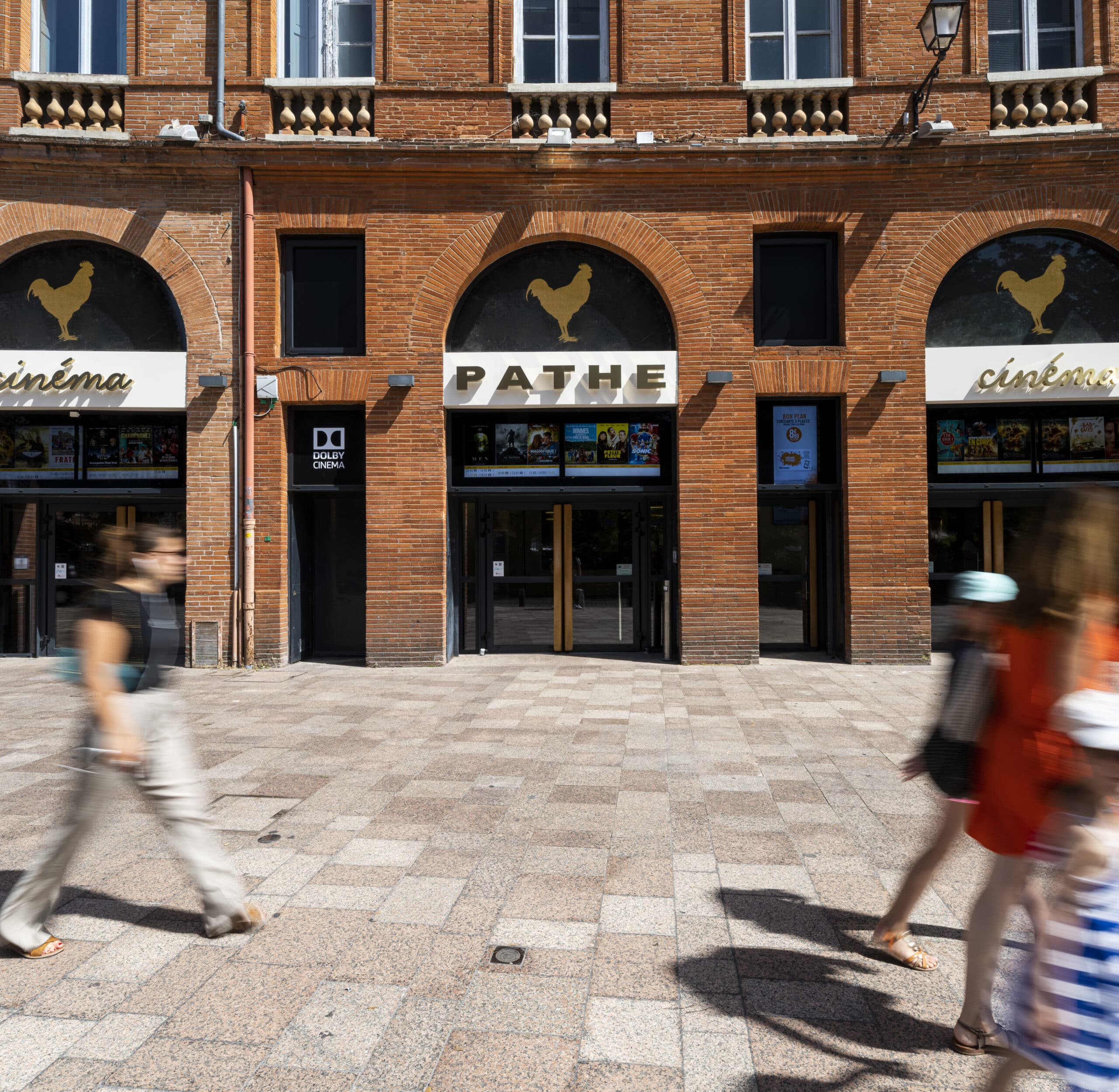 Façade extérieure du cinéma à la lumière du jour avec du public devant et le logo Pathé apparent.