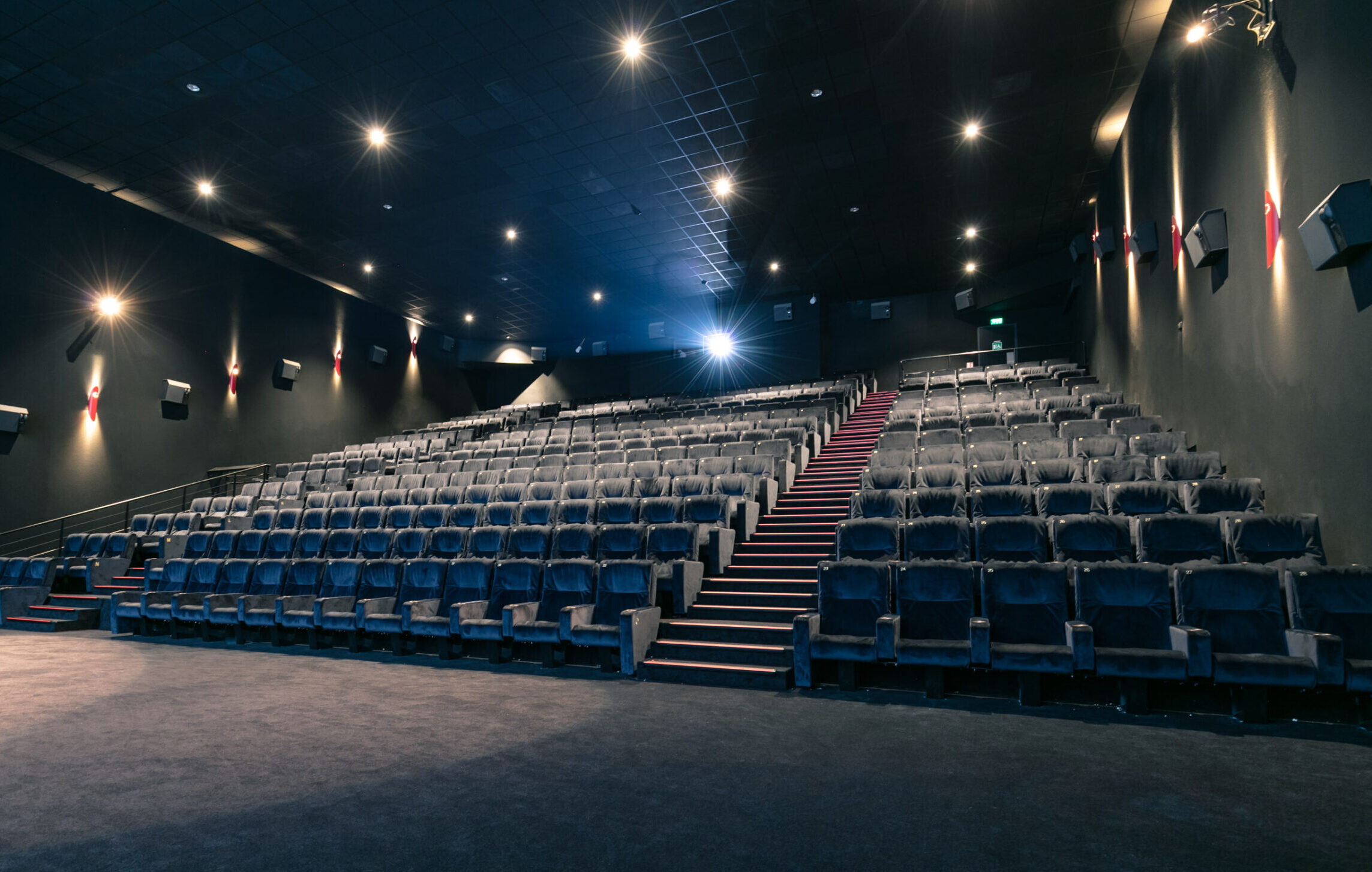 Grande salle de cinéma équipée de fauteuils en cuir noir et de la technologie Dolby.