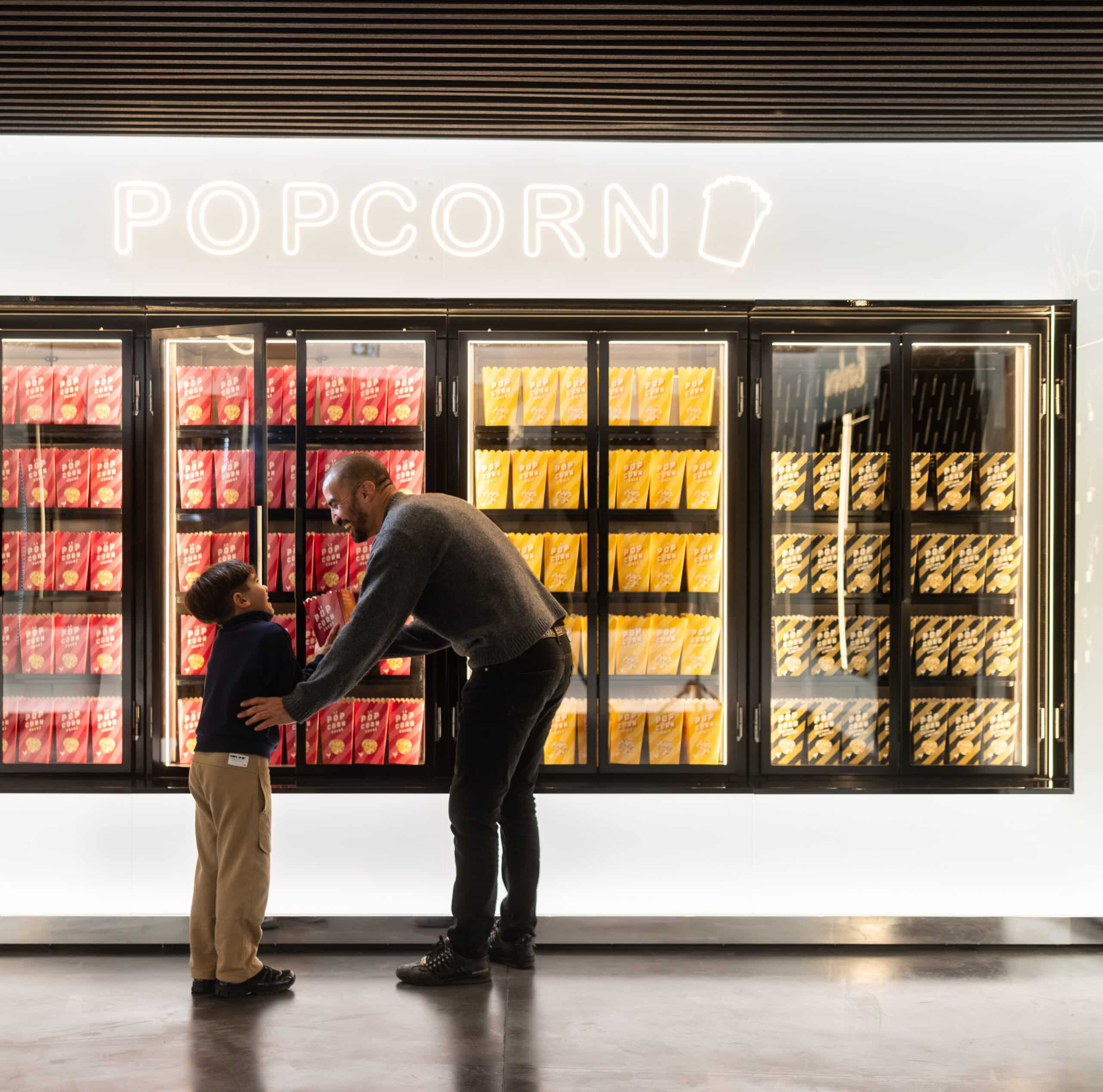 Espace confiserie du cinéma Pathé avec comptoir de pop-corn, distributeurs de boissons en libre-service et îlots de snacks et confiseries.