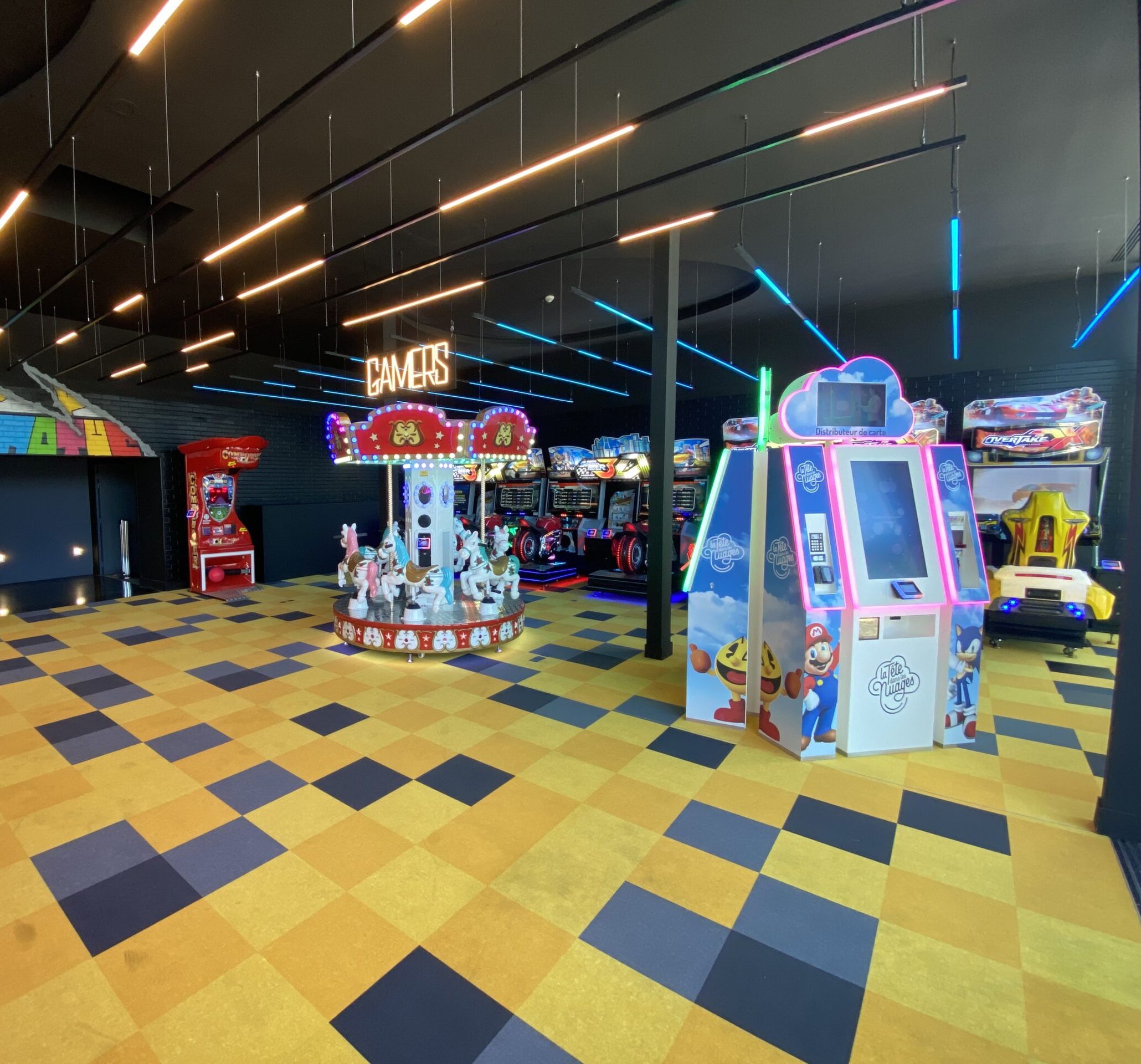 Espace Pathé Games avec différentes machines d’arcade et de jeux vidéo, éclairage néon coloré, ambiance moderne et ludique, proposant des jeux pour tous les âges dans un cadre convivial.
