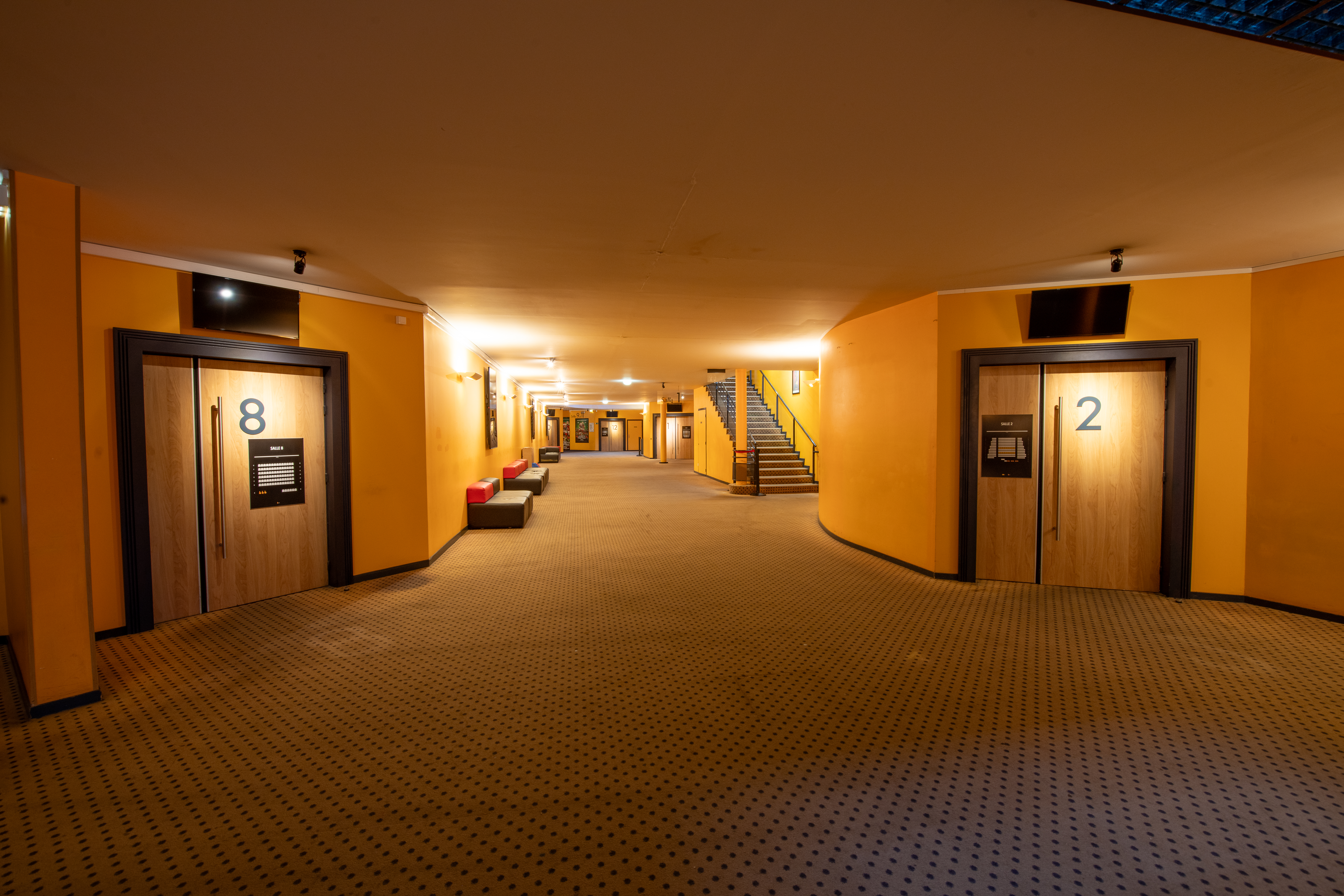 Grand espace de réception dans le hall du cinéma, éclairé par des lumières chaudes créant une ambiance chaleureuse.