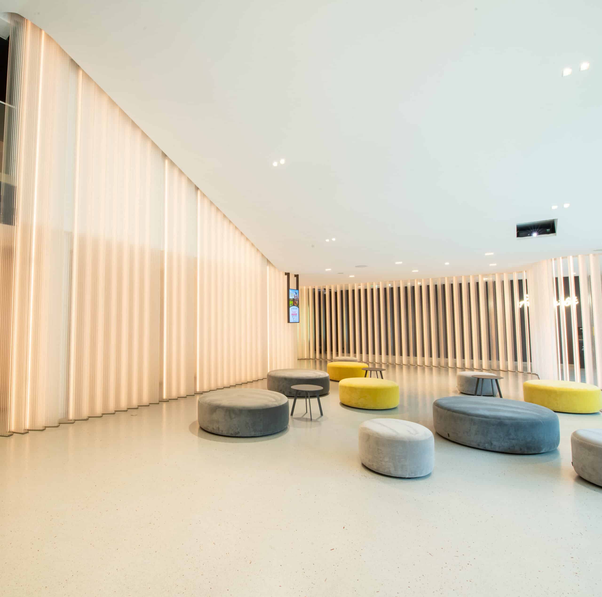 Espace cocktail du cinéma à la lumière du jour grâce à ses grandes baies vitrées, équipé d'un mobilier de réception, idéal pour des moments conviviaux et des réceptions.