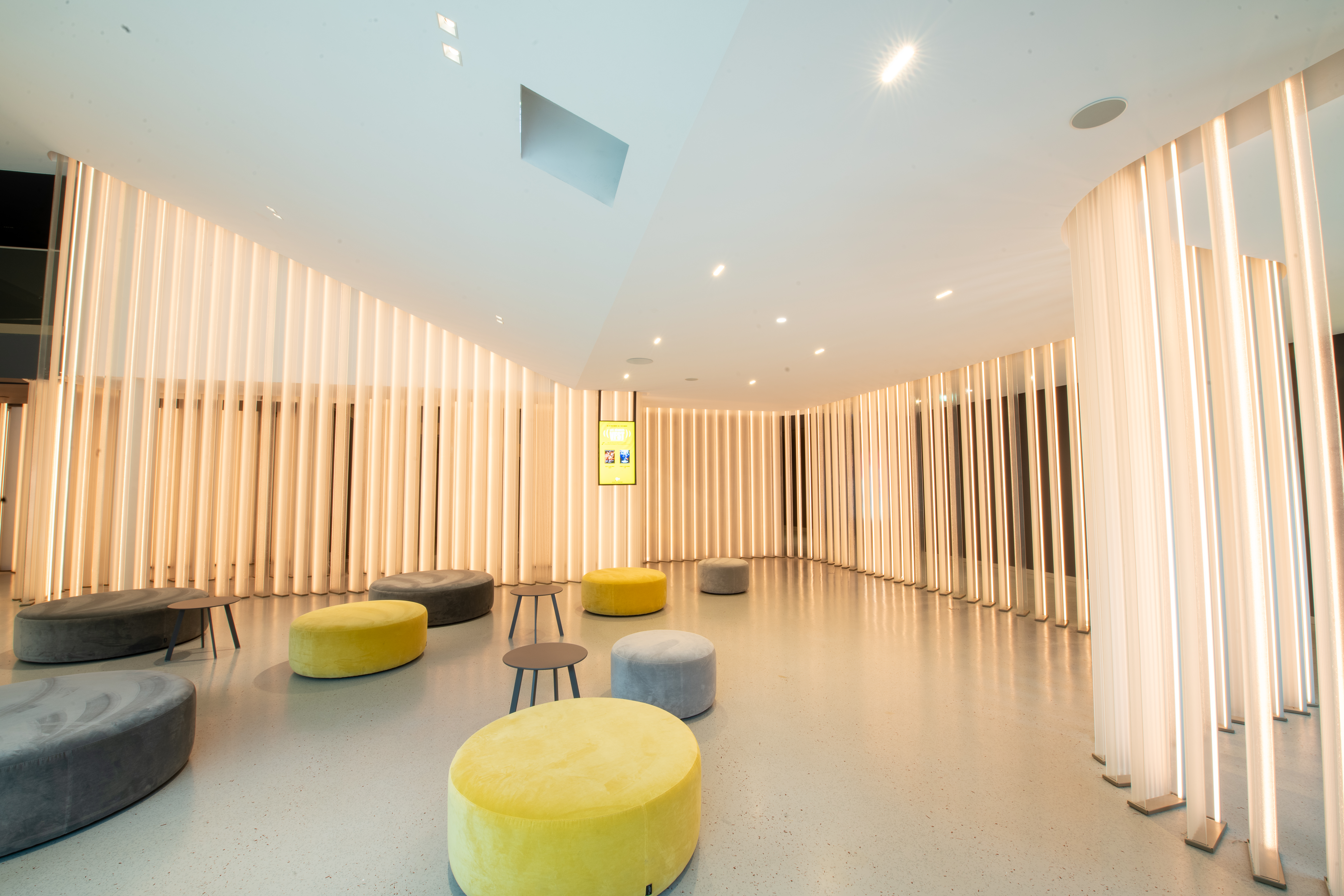 Espace cocktail du cinéma à la lumière du jour grâce à ses grandes baies vitrées, équipé d'un mobilier de réception, idéal pour des moments conviviaux et des réceptions.