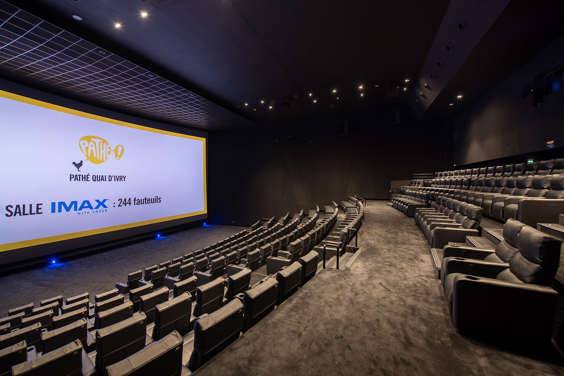 Grande salle de cinéma équipée de fauteuils en cuir noir et de la technologie IMAX.