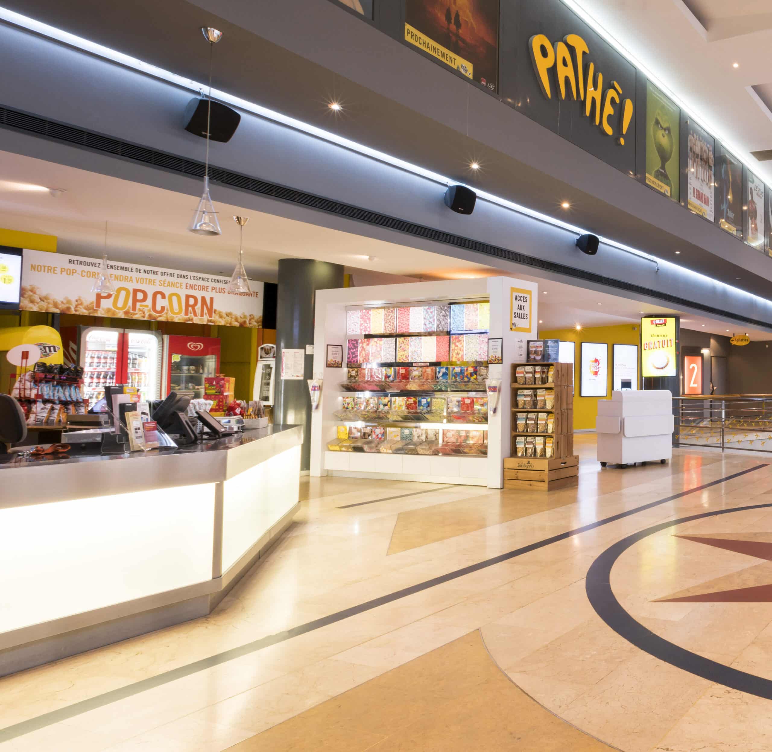 Hall d'entrée du cinéma Pathé Boulogne où l'on voit apparaitre l'espace confiserie et les affiches de film.