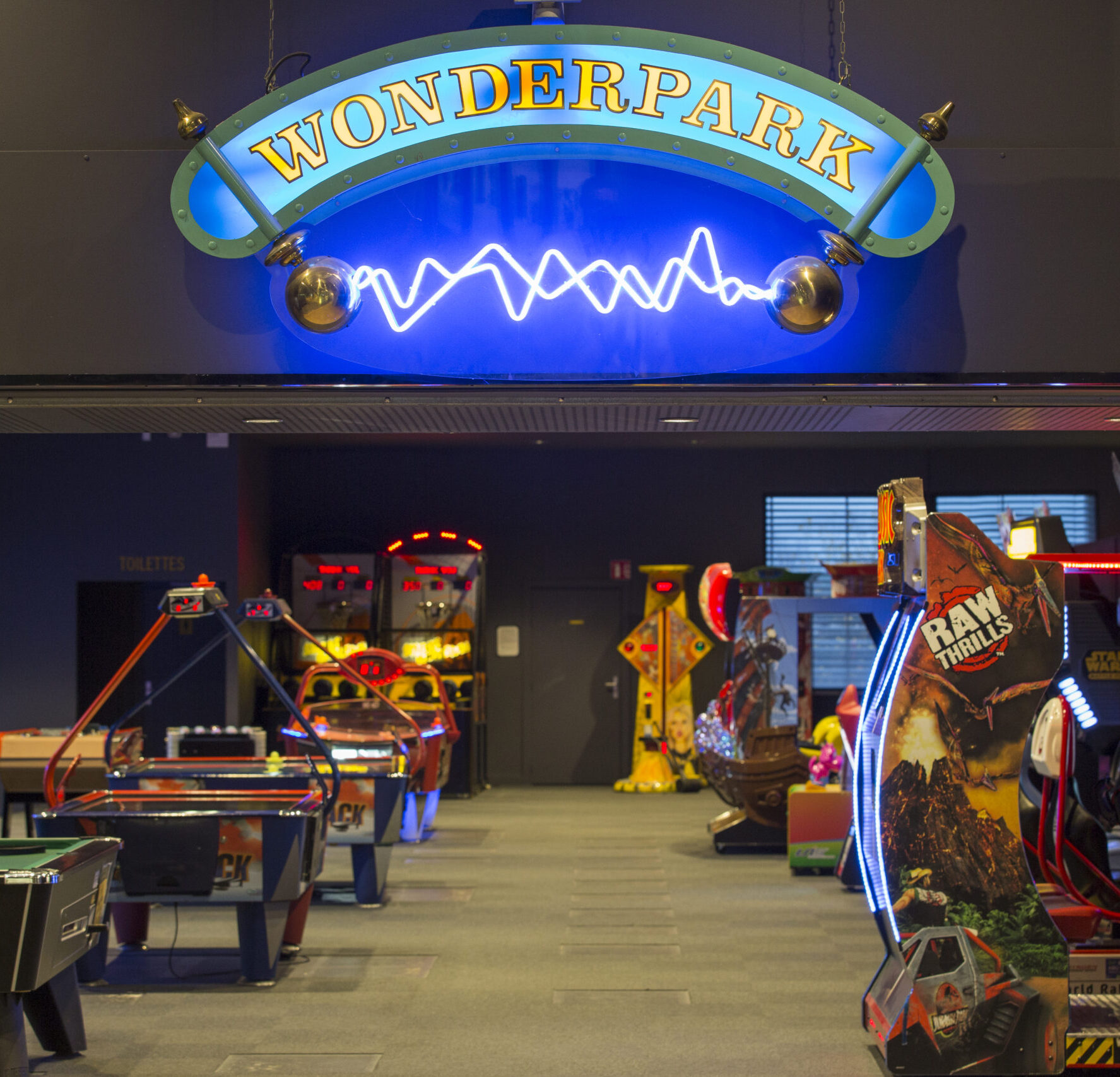 Espace Pathé Games avec différentes machines d’arcade et de jeux vidéo, éclairage néon coloré, ambiance moderne et ludique, proposant des jeux pour tous les âges dans un cadre convivial.