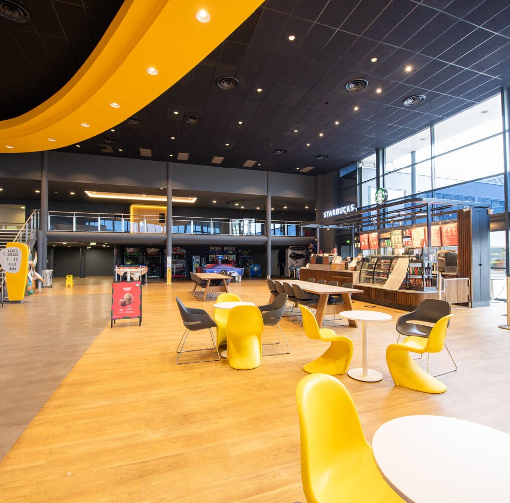 Espace cocktail du cinéma, équipé de tables, chaises et canapés, idéal pour des moments conviviaux et des réceptions.