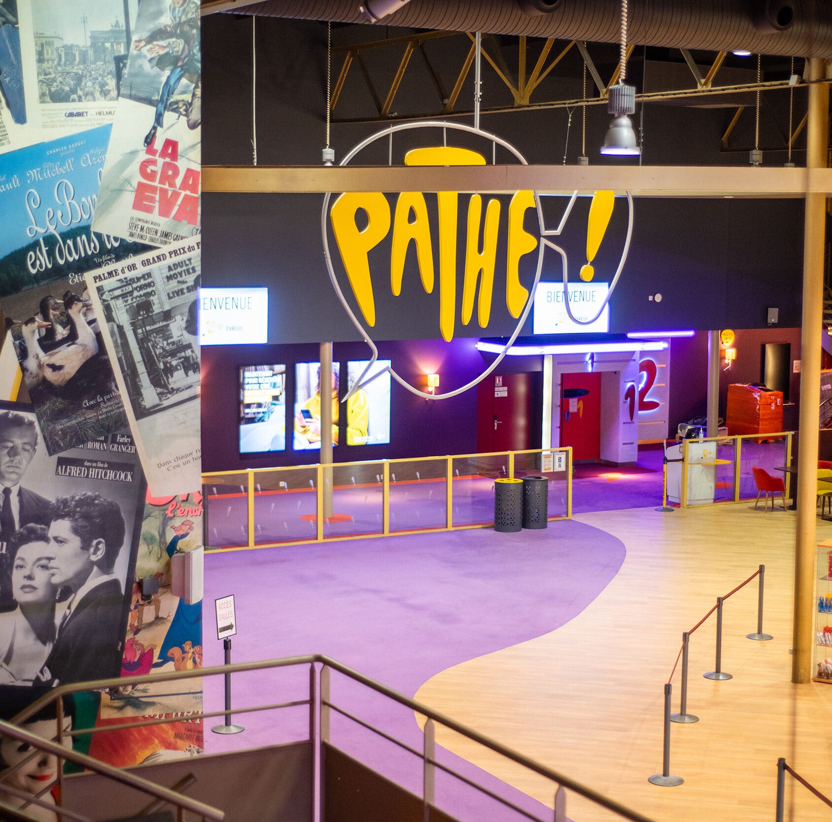 Entrée des salles de cinéma Pathé avec tapis violet, une zone de confiseries, des affiches de films classiques et un décor coloré et accueillant.
