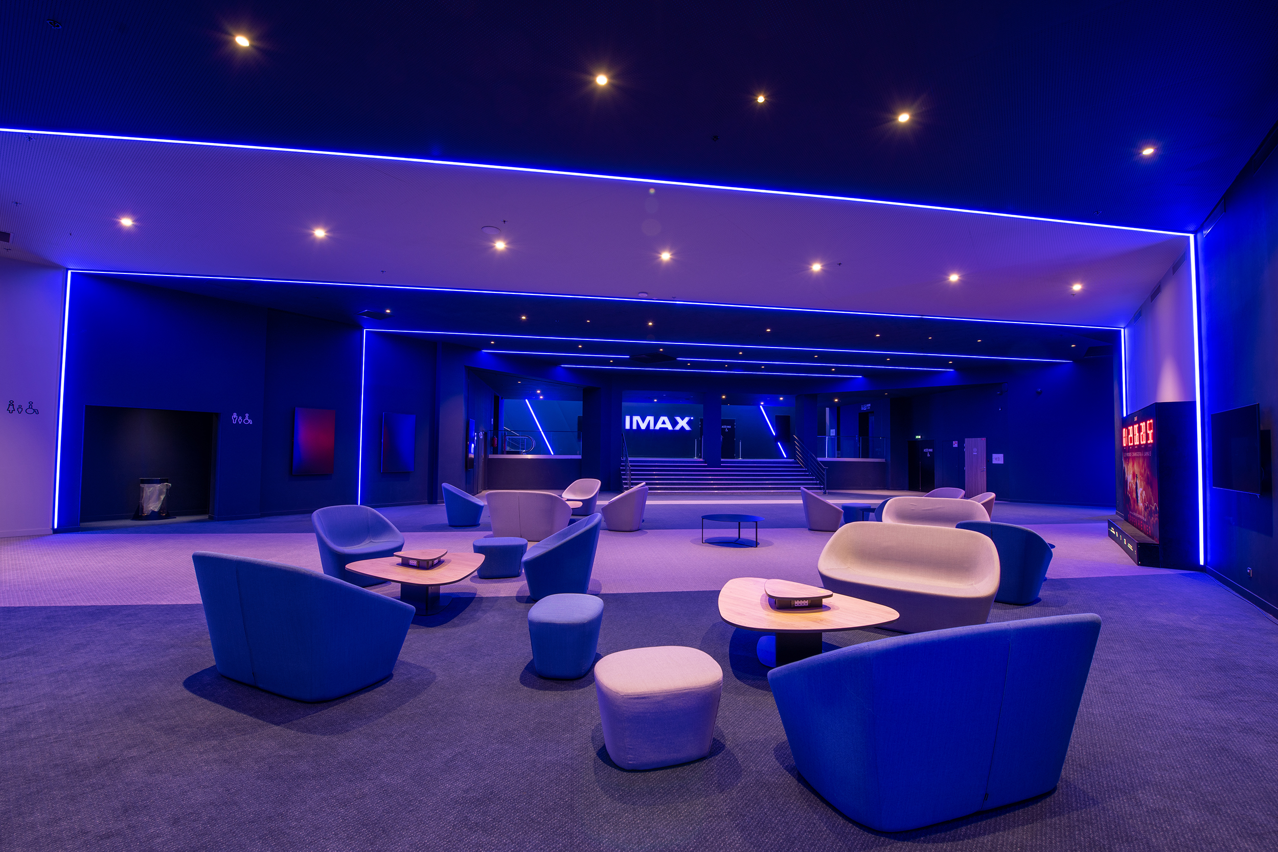 Espace cocktail du cinéma, situé devant la salle IMAX, équipé de tables, chaises et canapés, idéal pour des moments conviviaux et des réceptions.