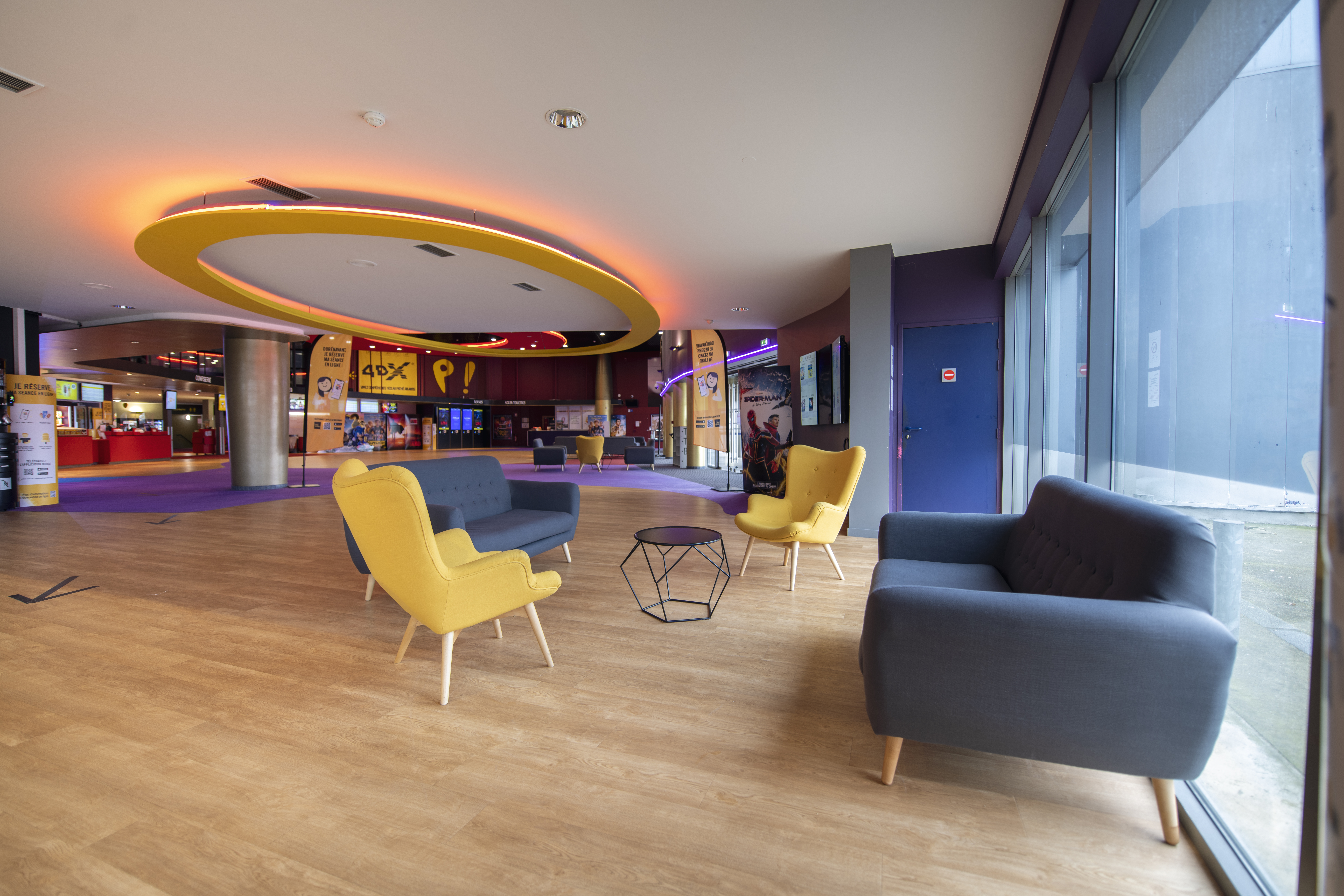 Espace cocktail du cinéma à la lumière du jour situé dans le hall d'accueil, équipé d'un mobilier de réception, idéal pour des moments conviviaux et des réceptions.