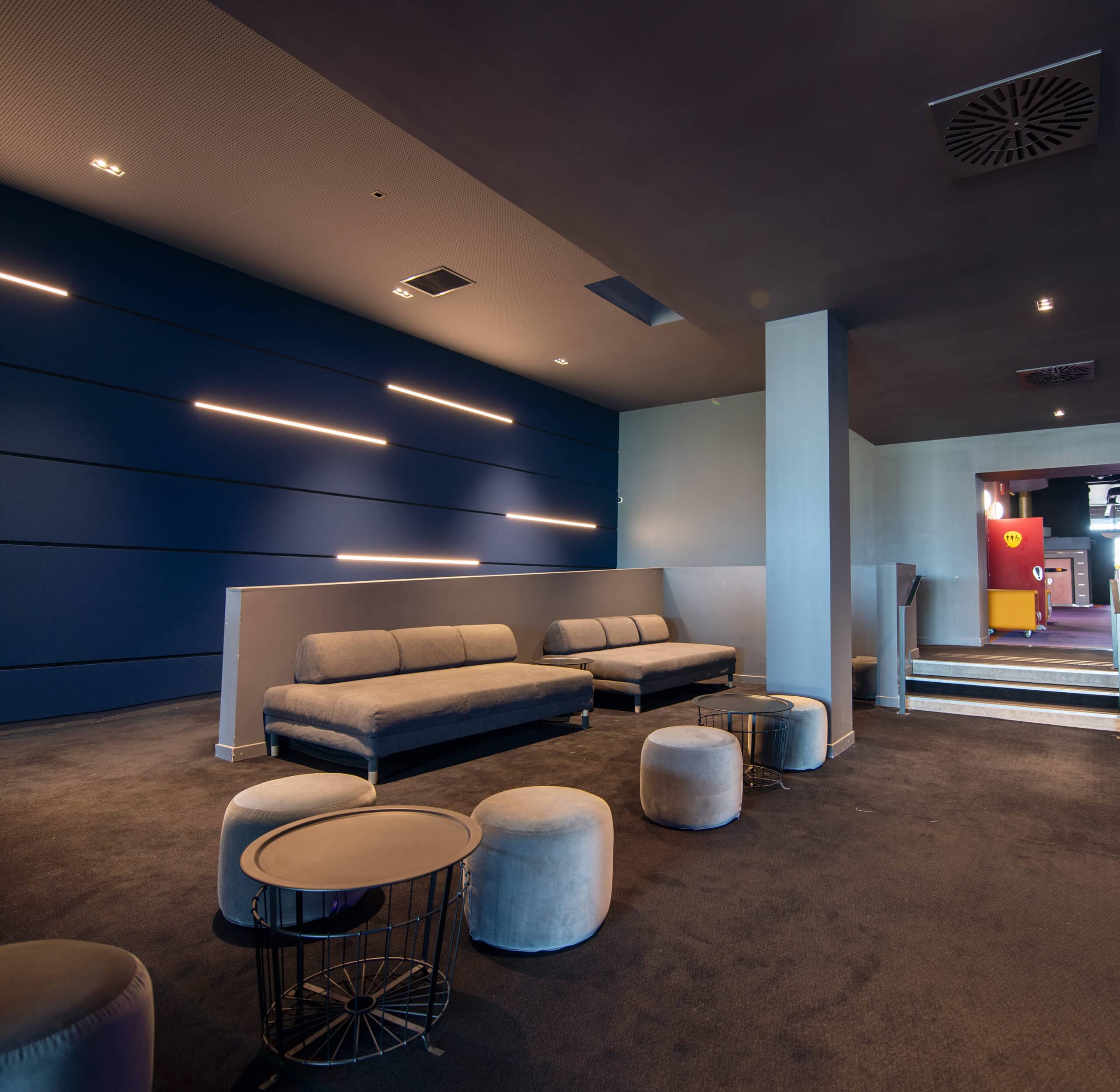 Espace de réception, éclairé par une lumière tamisée et par la lumière naturelle avec des canapés et du mobilier de salon gris.