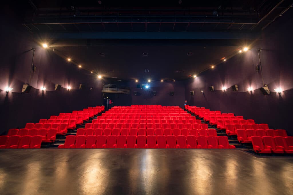 Vu d'ensemble de face d'une grande salle avec ses fauteuils en velours rouge.