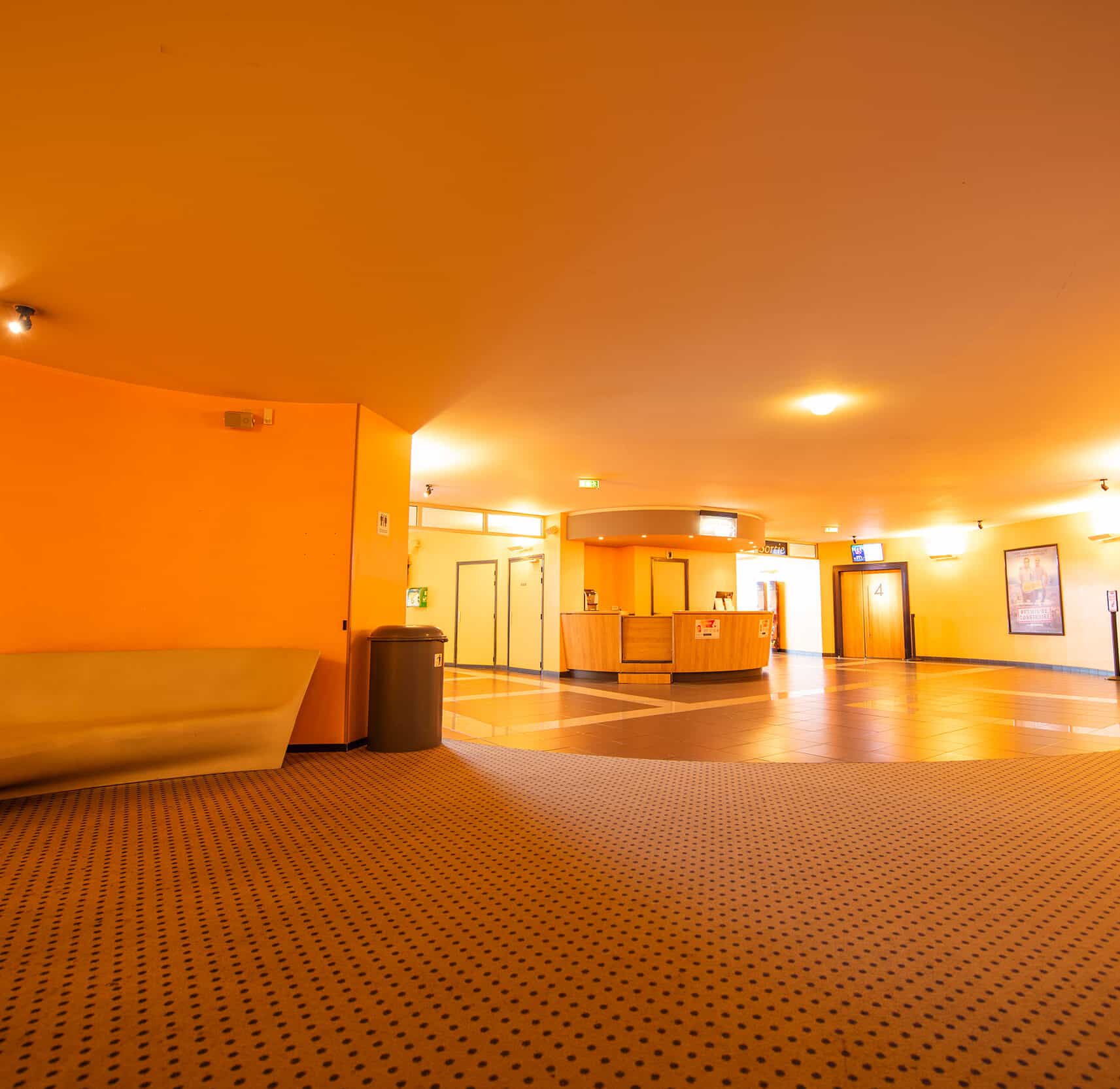 Grand espace de réception dans le hall du cinéma, éclairé par des lumières chaudes créant une ambiance chaleureuse.