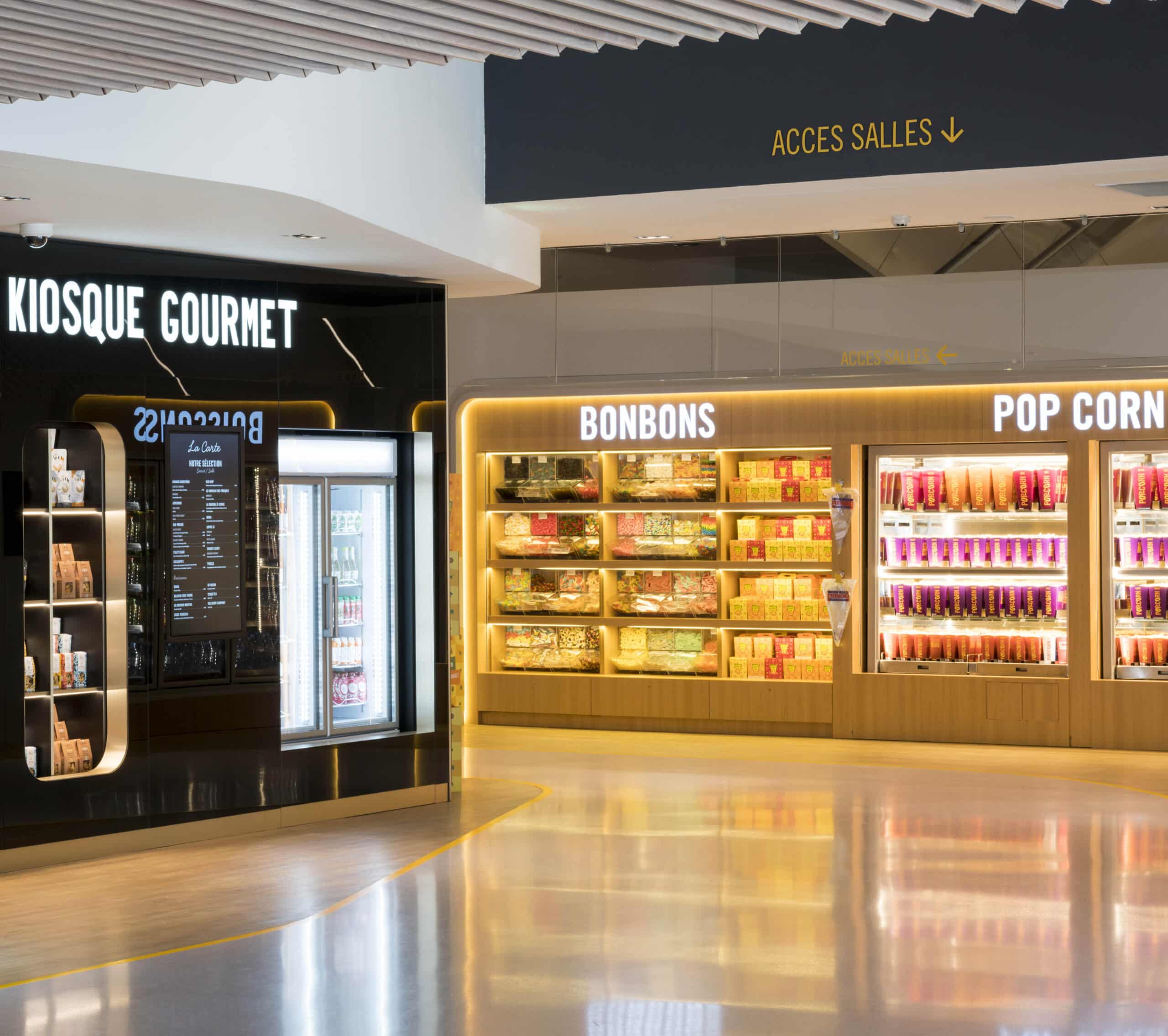 Espace confiserie du cinéma Pathé avec comptoir de pop-corn, distributeurs de boissons en libre-service et îlots de snacks et confiseries.