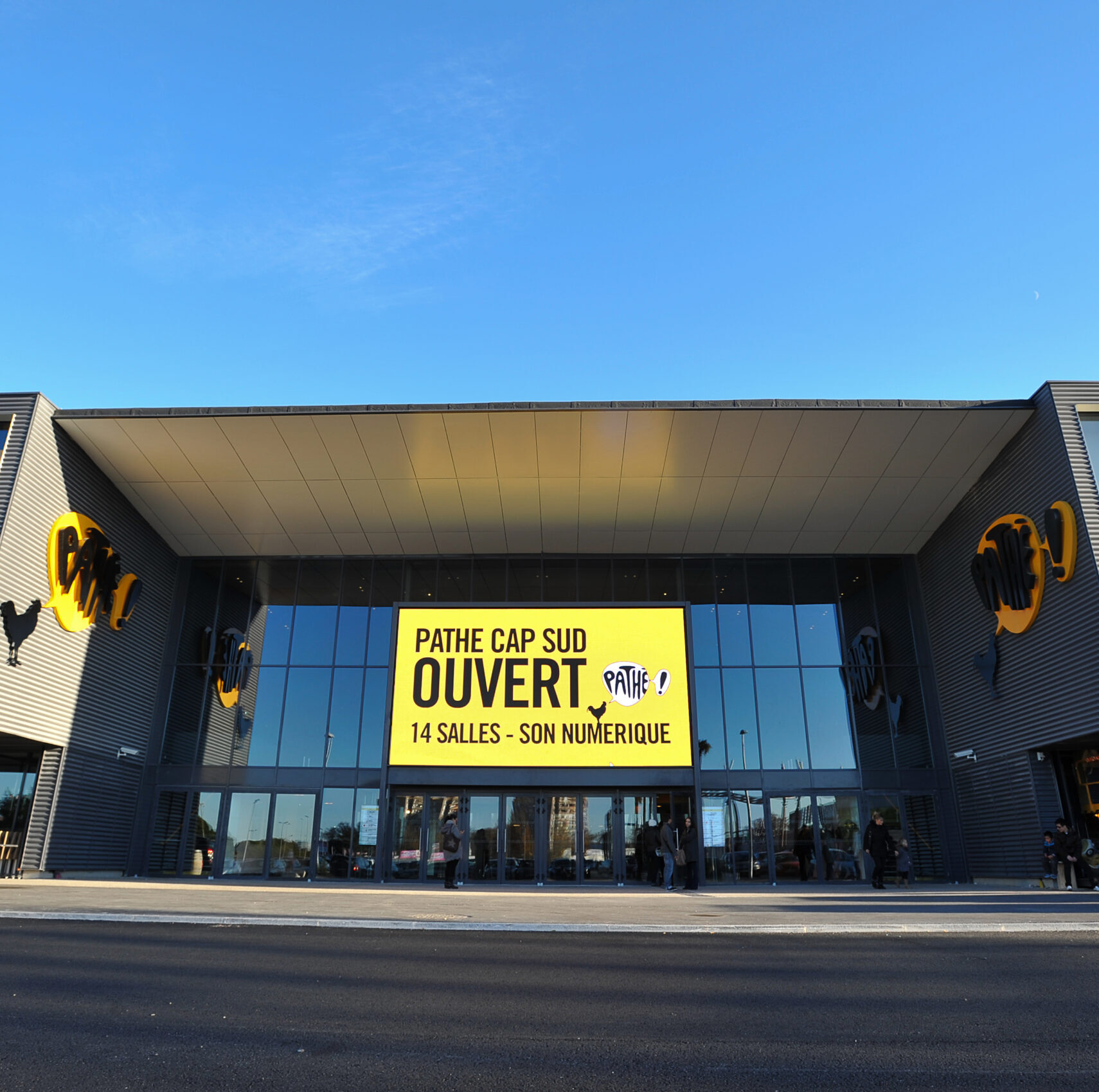Façade extérieure du cinéma à la lumière du jour avec le logo Pathé apparent.