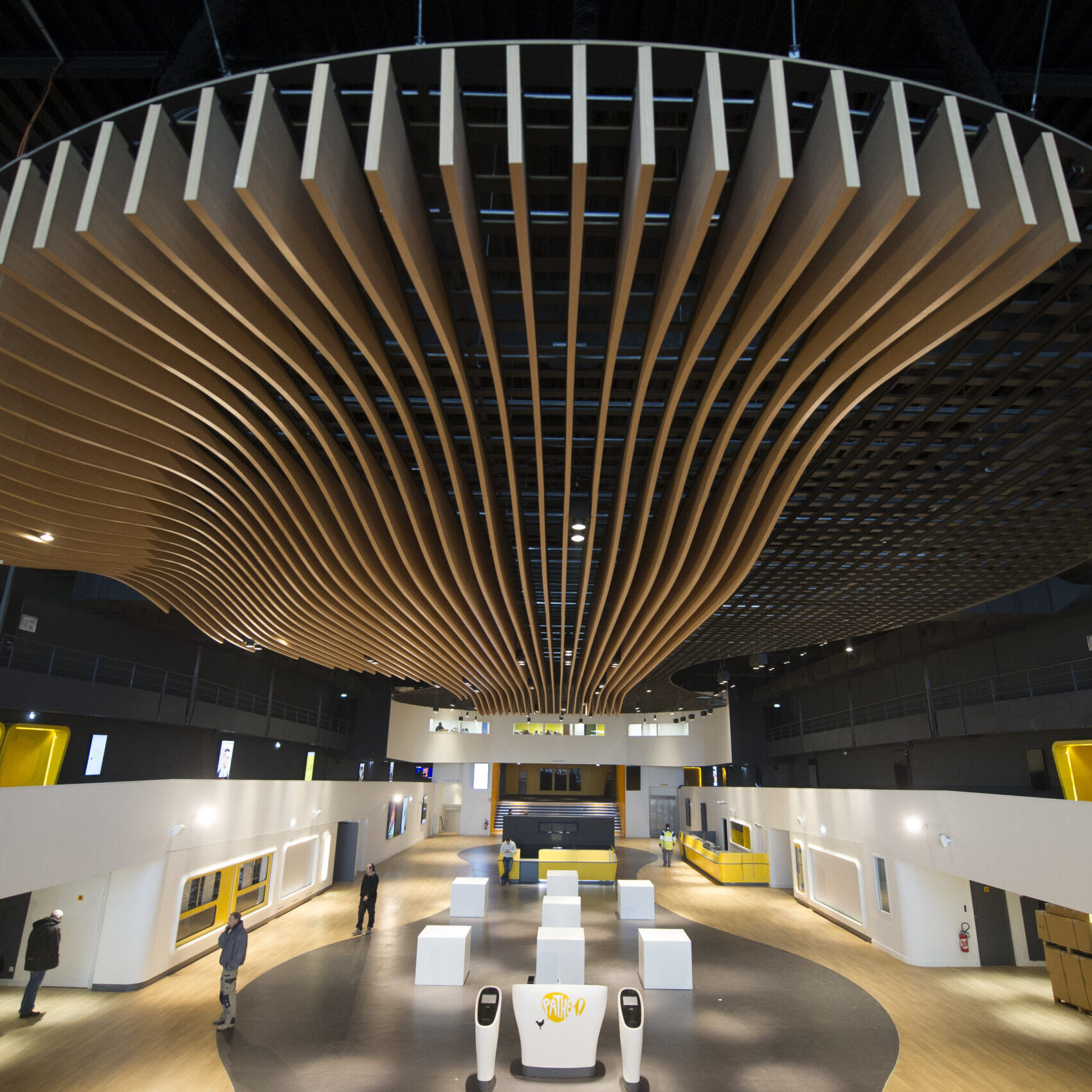 Grand hall du cinéma avec plafond en bois ondulé, espaces modernes et design épuré.