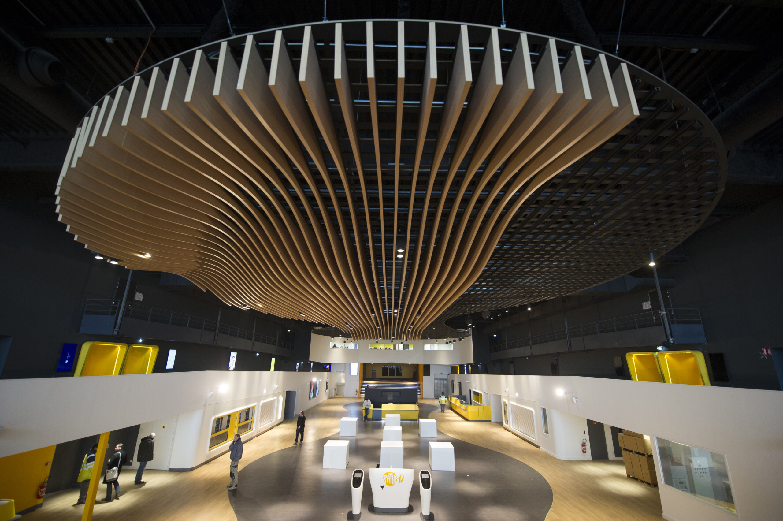 Grand hall du cinéma avec plafond en bois ondulé, espaces modernes et design épuré.