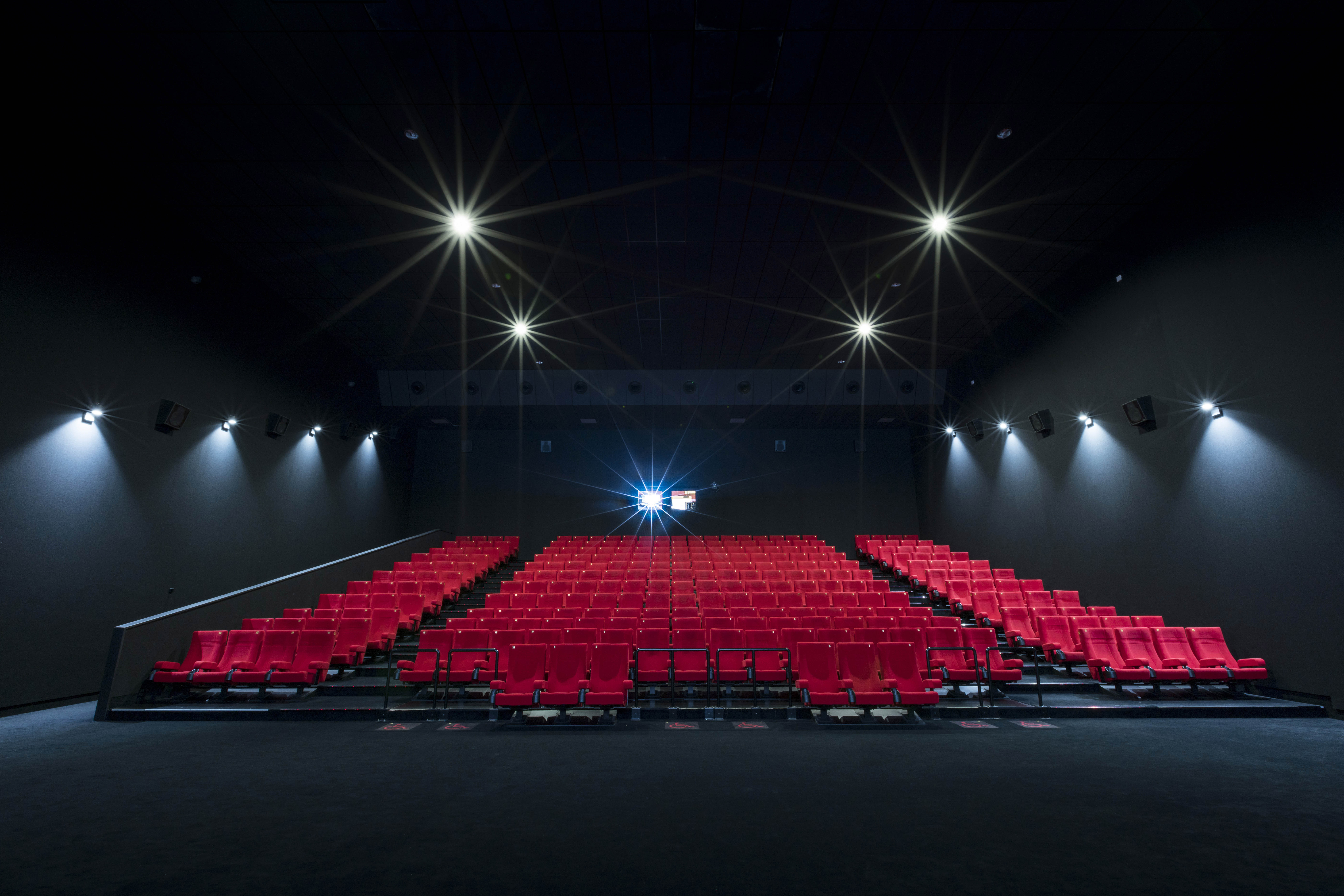 Vu d'ensemble de face d'une grande salle avec ses fauteuils en velours rouge.