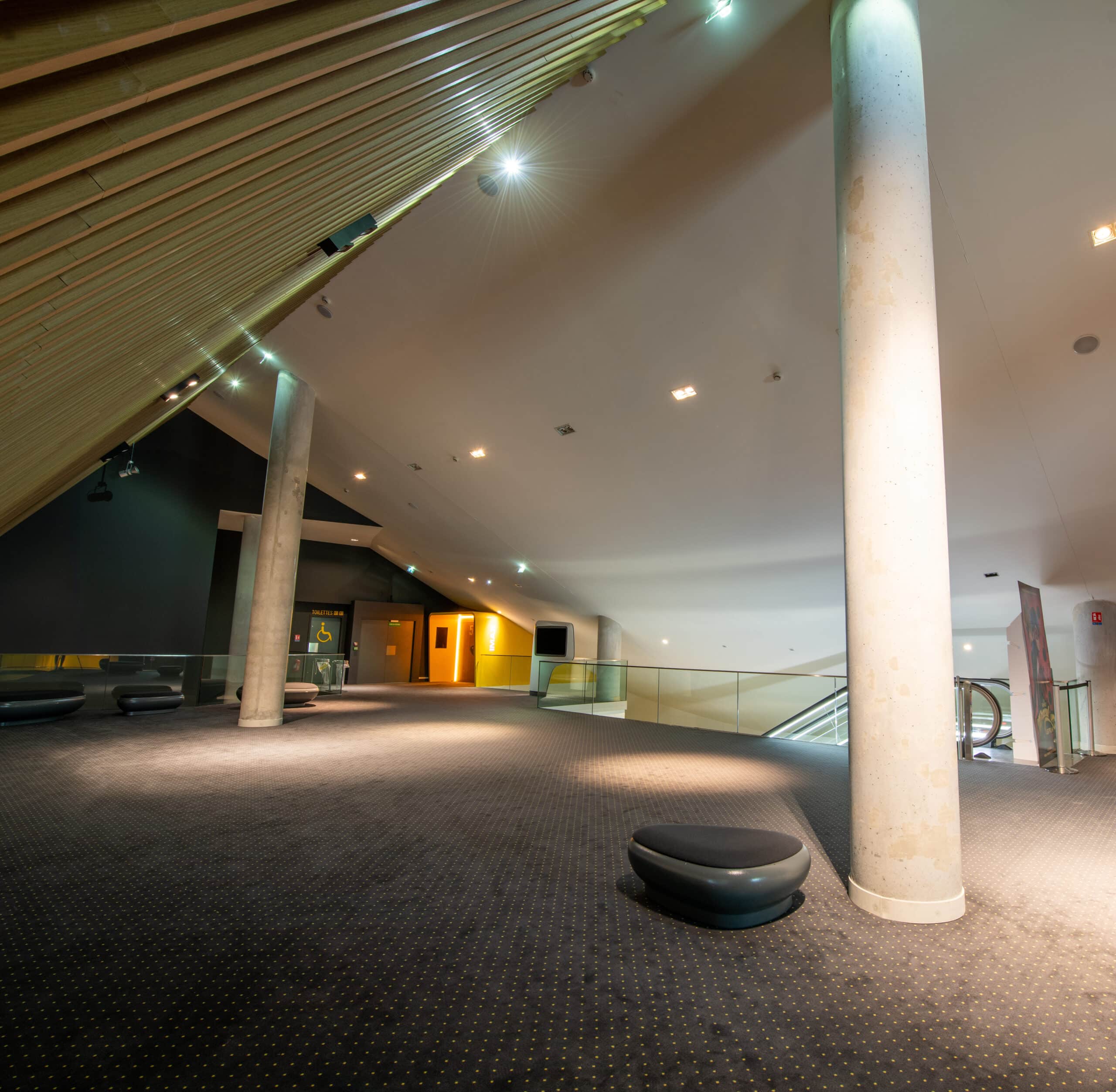Espace de réception situé sur la mezzanine du cinéma, éclairé par une lumière blanche et aménagé avec du mobilier de réception.