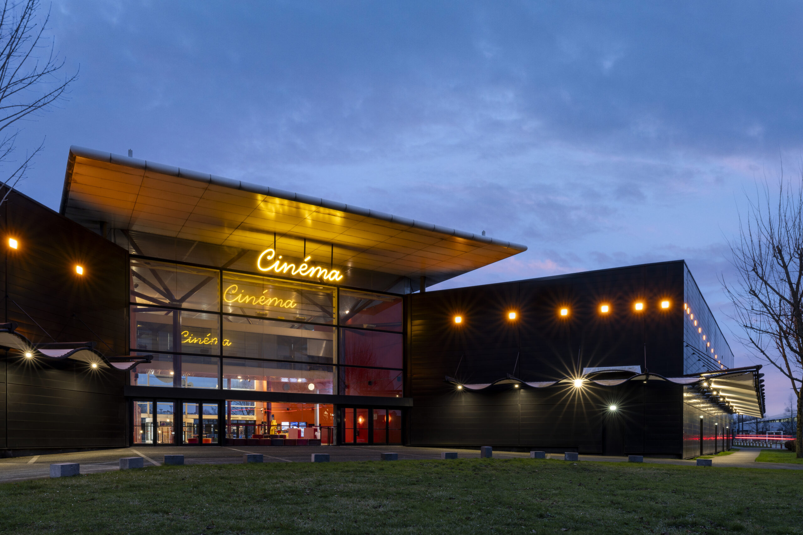 Façade extérieure du cinéma éclairée à la tombée de la nuit.