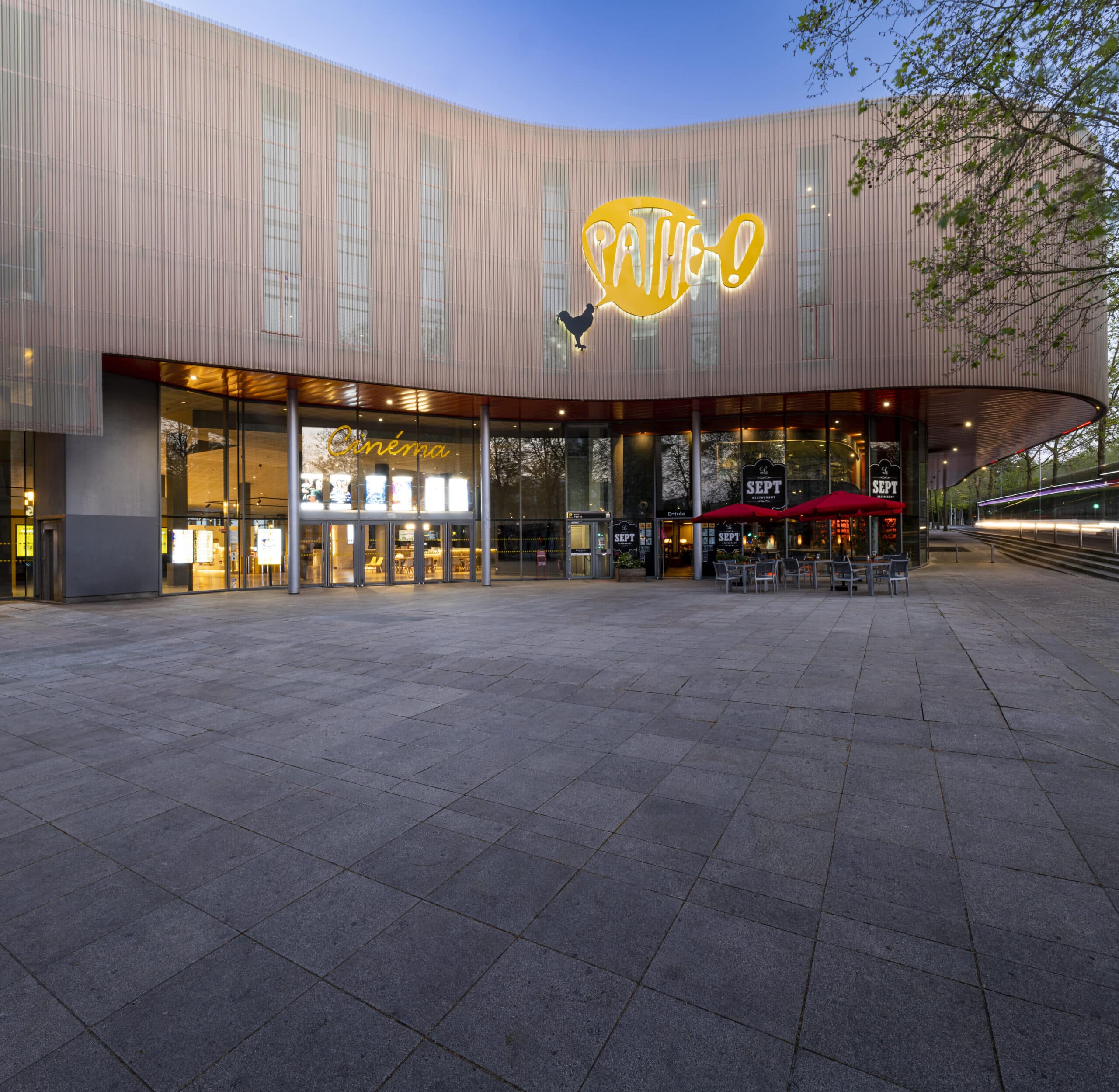 Façade extérieure du cinéma à la lumière du jour avec le logo Pathé illuminé apparent.
