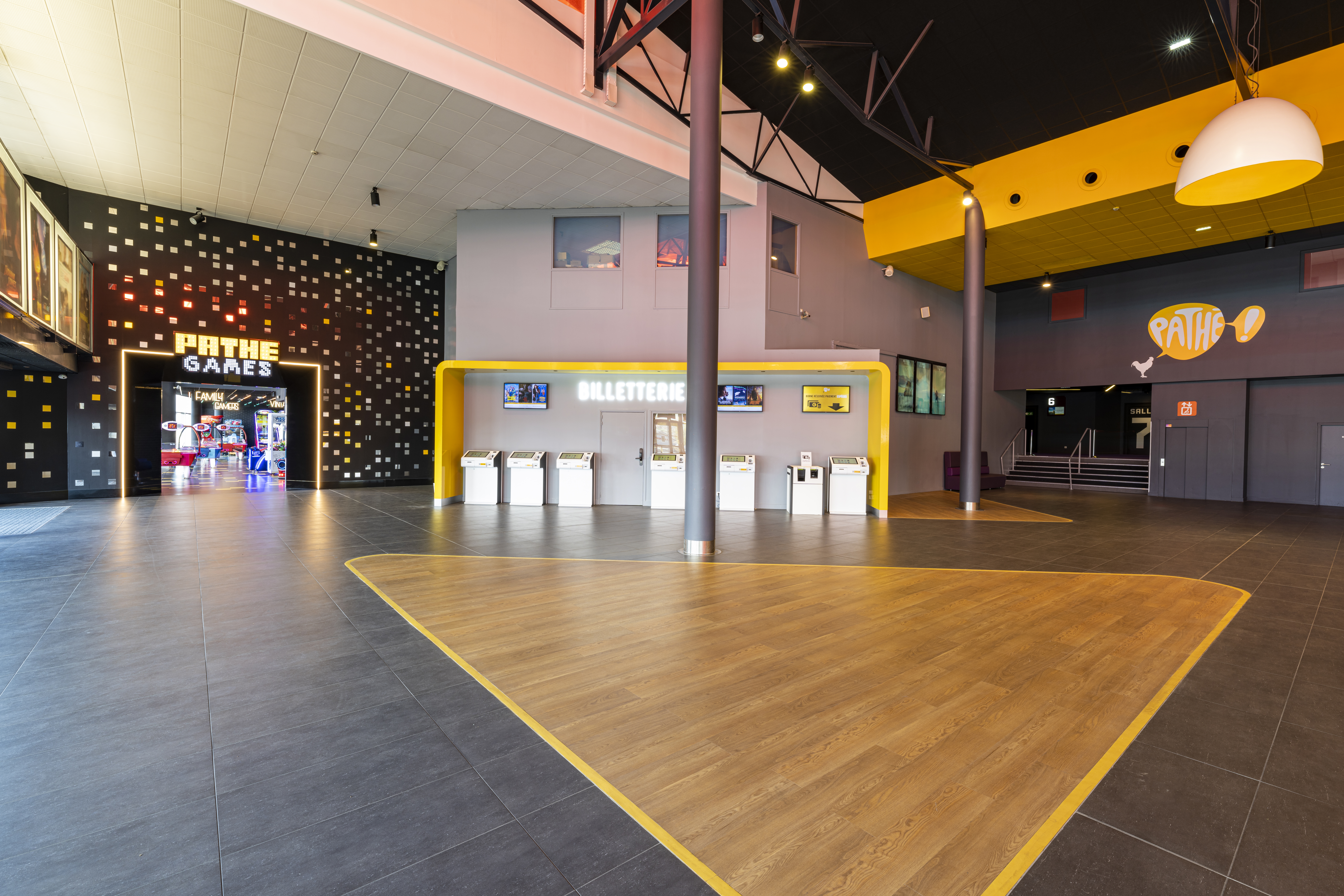 Hall du cinéma avec billetterie moderne, entrée lumineuse vers Pathé Games et design élégant.