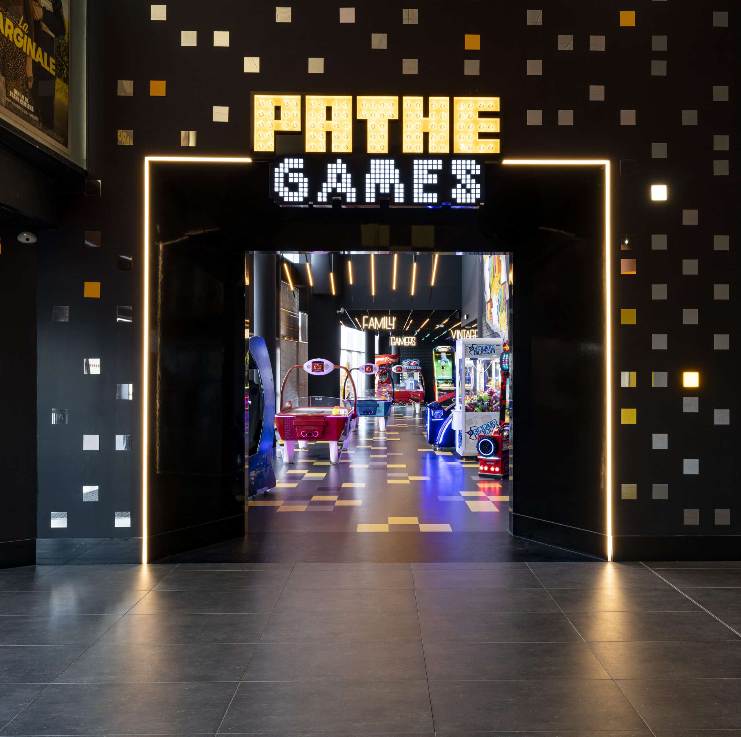 Entrée lumineuse du centre Pathé Games avec jeux d’arcade colorés visibles à l’intérieur et mur décoré de motifs géométriques