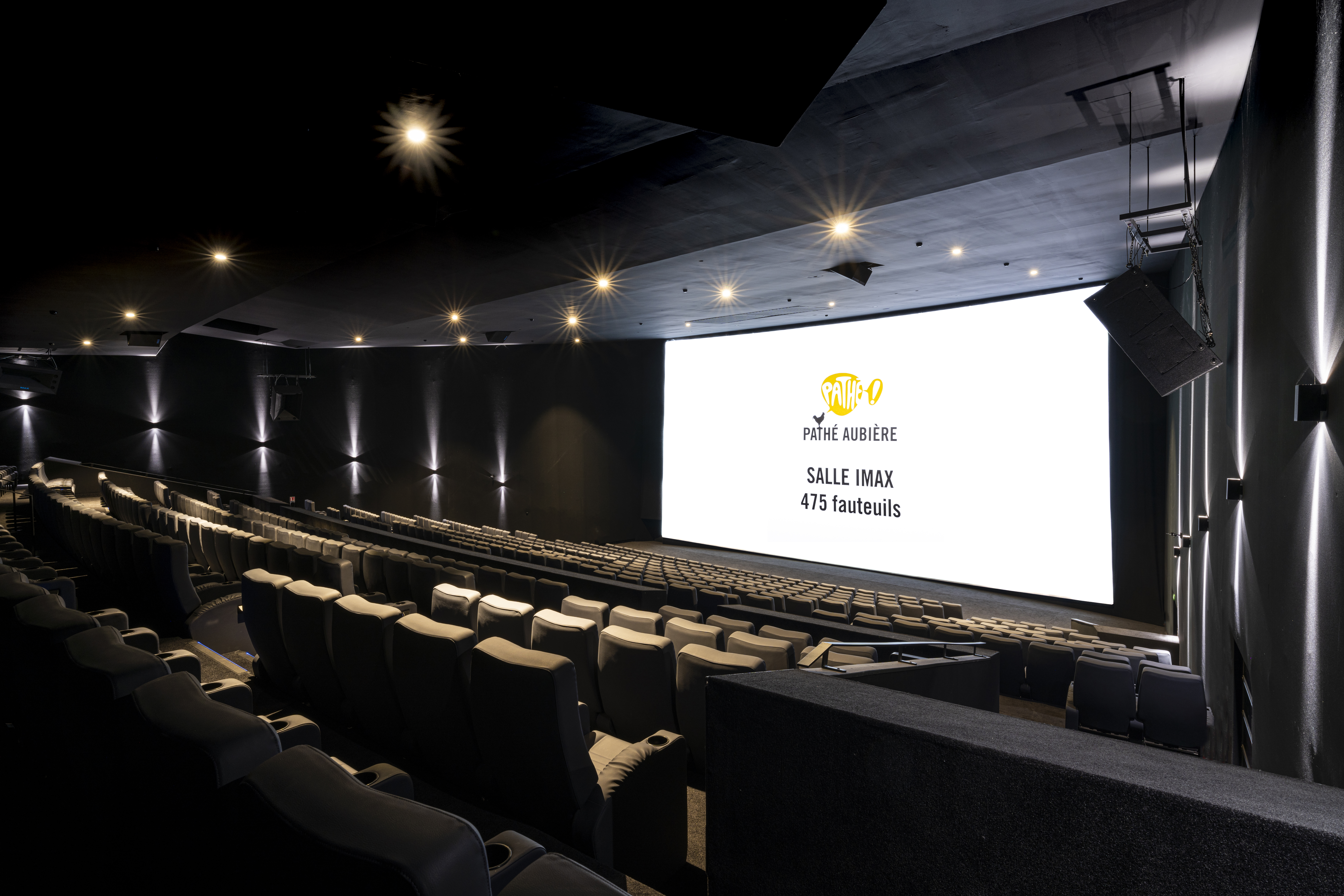 Vue de derrière de la salle IMAX du cinéma Pathé Aubière avec ses fauteuils en cuirs noirs.