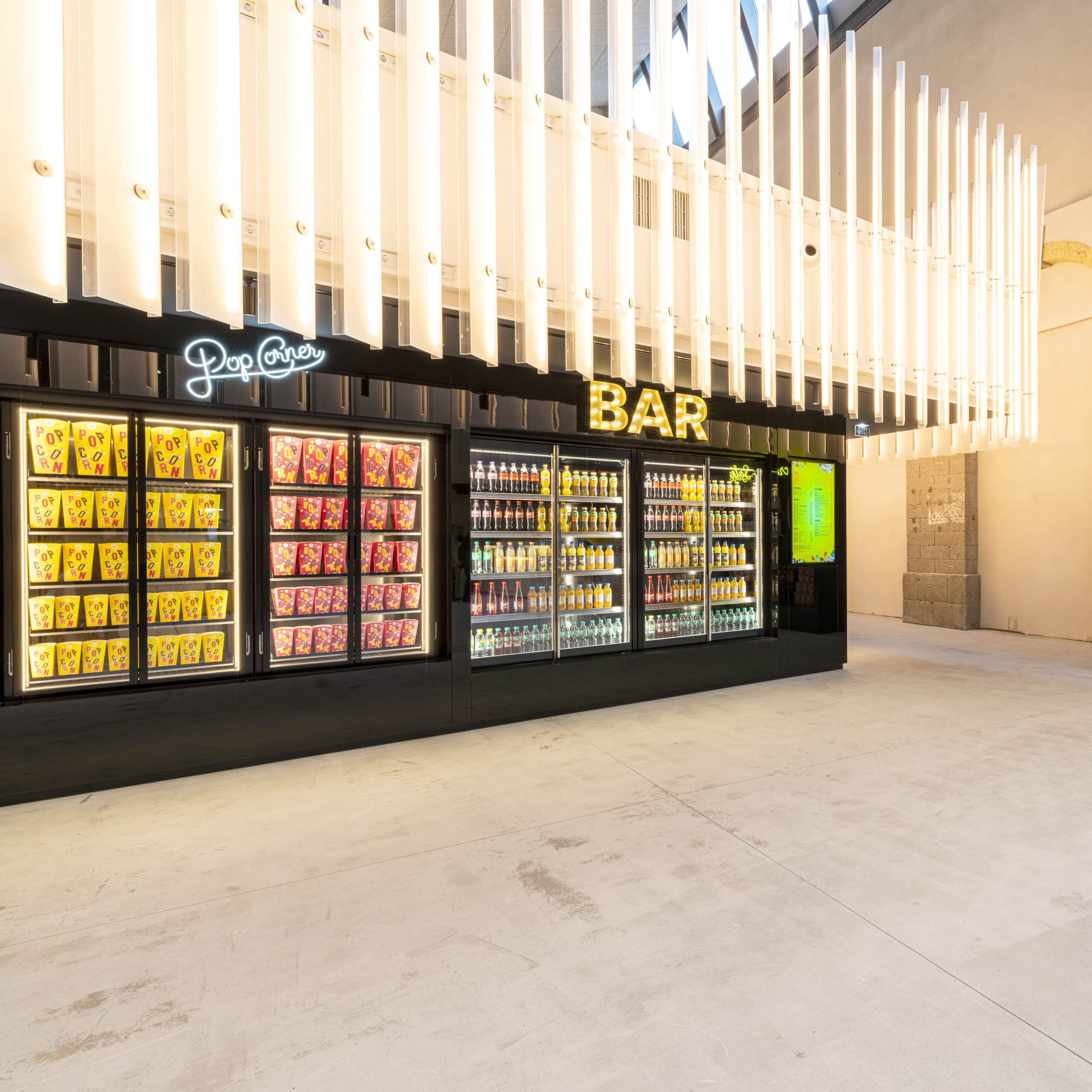 Espace confiserie du cinéma Pathé avec comptoir de pop-corn, distributeurs de boissons en libre-service.