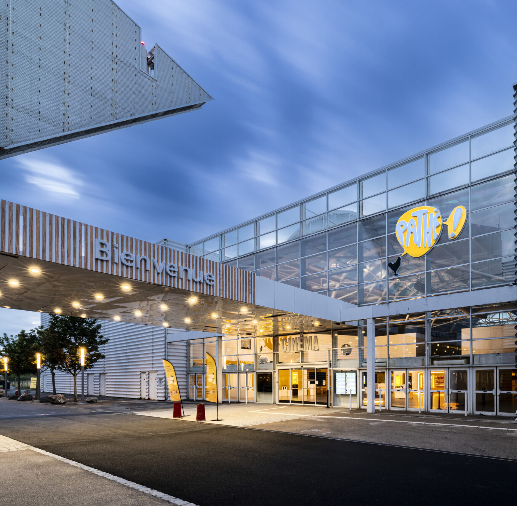 Façade extérieure du cinéma éclairée à la tombée de la nuit avec le logo Pathé mit en valeur.