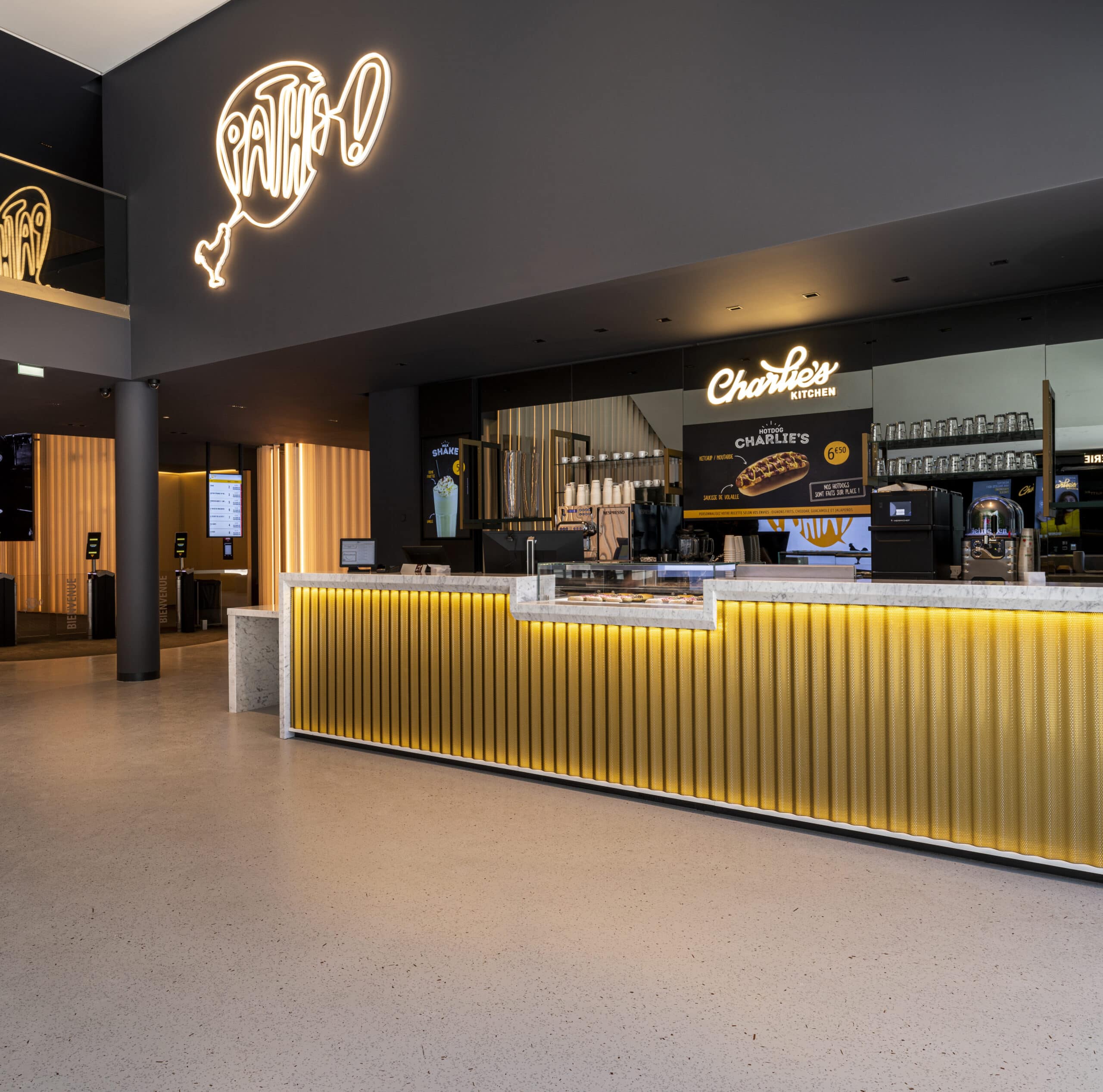 Comptoir lumineux de Charlie's Kitchen dans le cinéma Pathé, avec un design moderne, logo Pathé néon et espace de restauration.