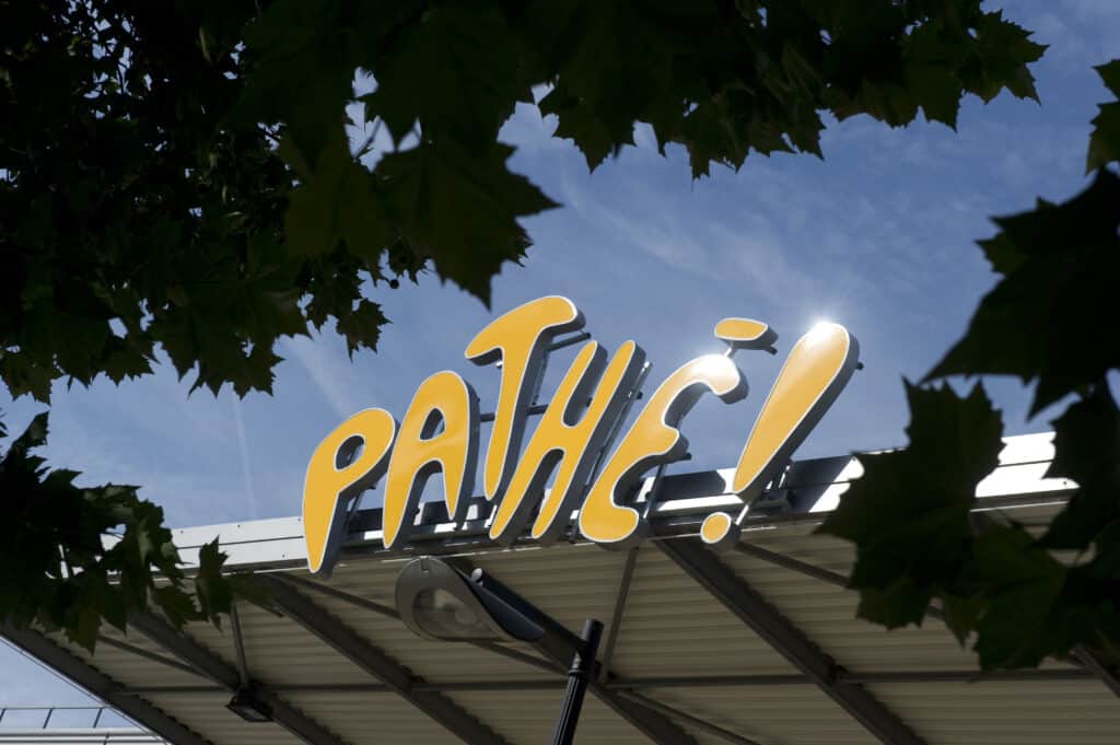Logo lumineux « Pathé ! » au dessus de la façade d'un cinéma.