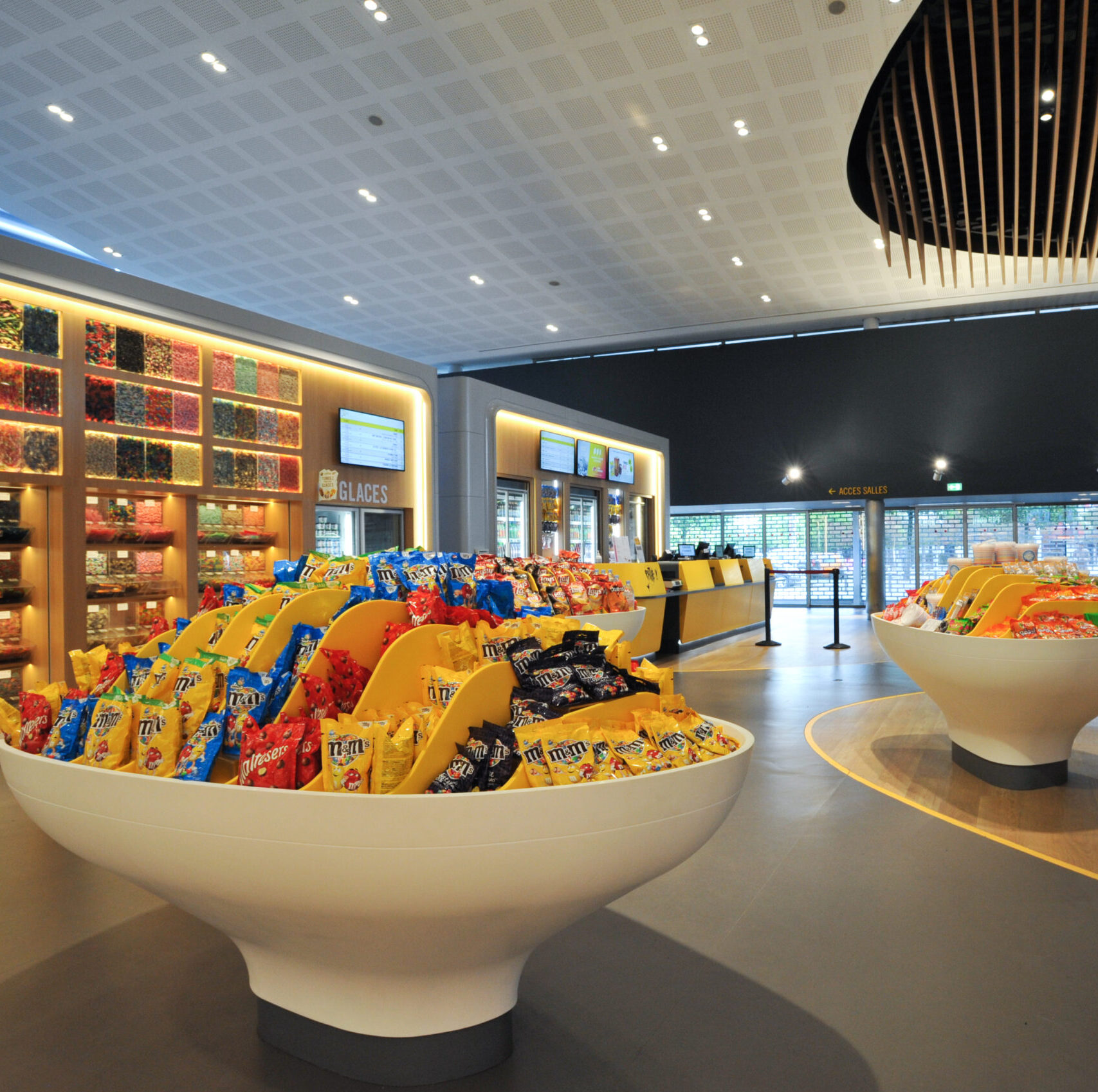 Espace confiserie du cinéma Pathé avec comptoir de pop-corn, distributeurs de boissons en libre-service et îlots de snacks et confiseries.