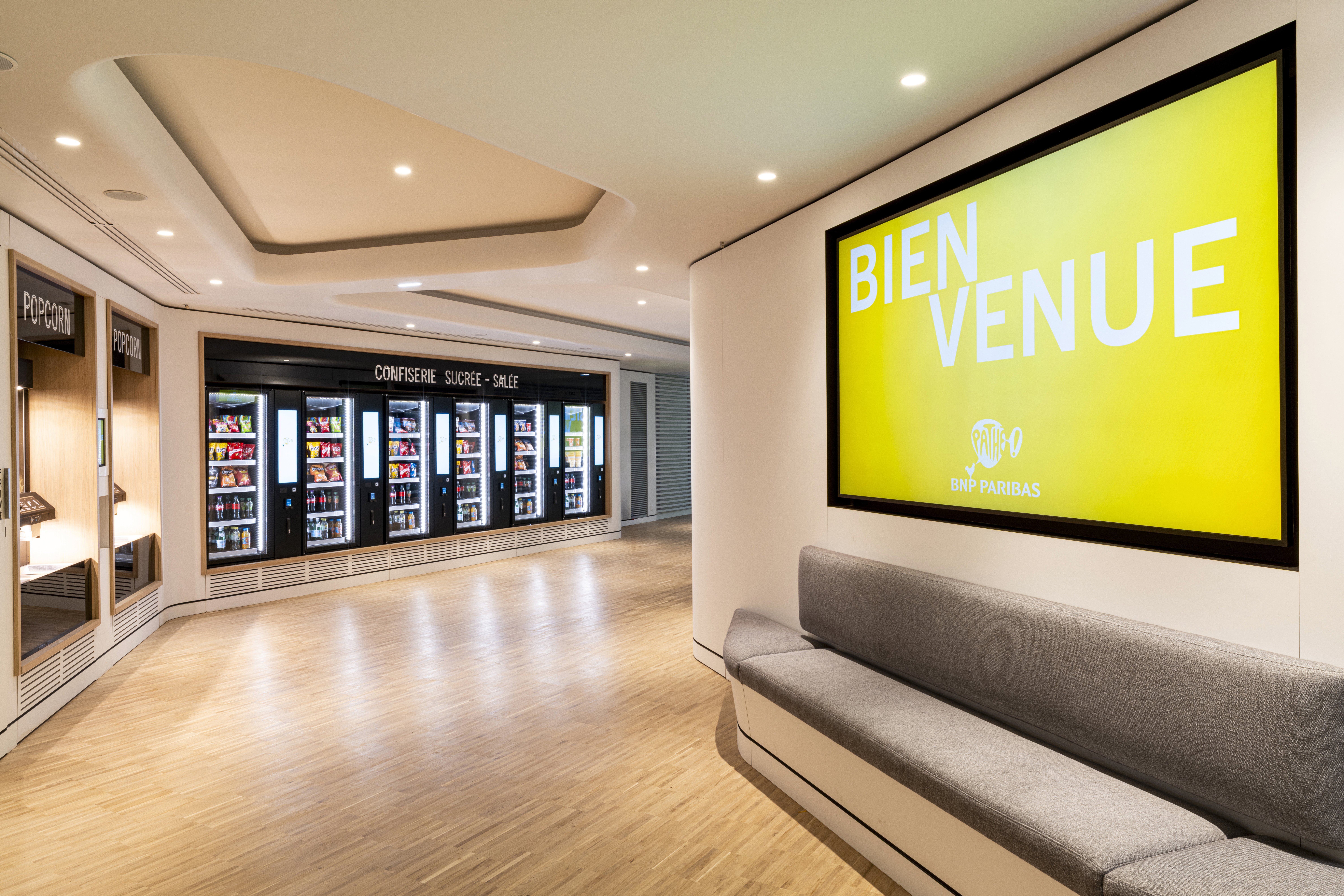 Espace d'accueil du cinéma avec des écrans lumineux « Bienvenue » et les distributeurs à pop corn.