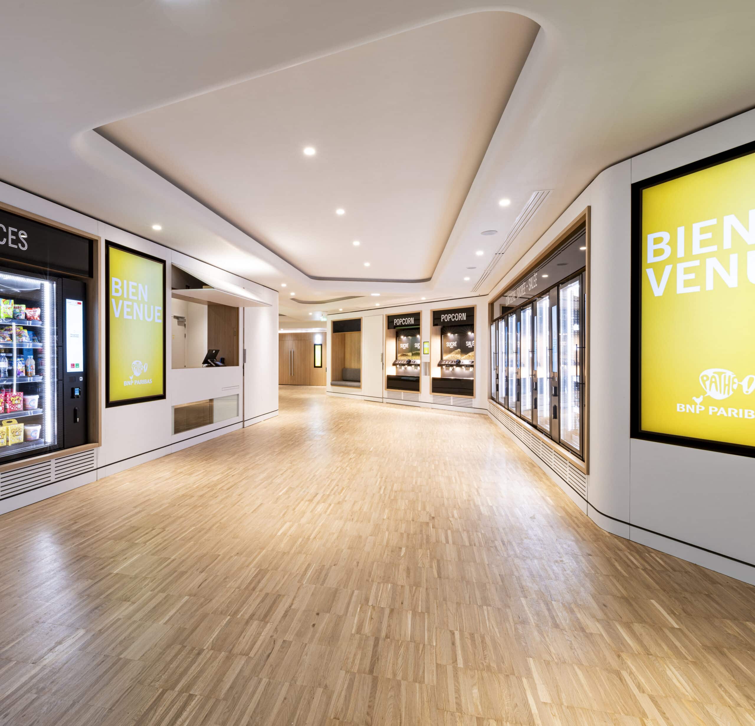 Espace d'accueil du cinéma avec des écrans lumineux « Bienvenue » et les distributeurs à pop corn.